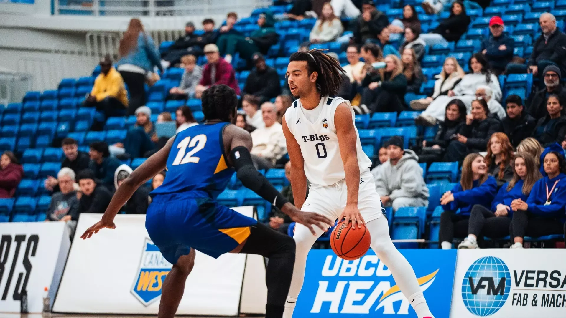 UBC's Nylan Roberts dribbling the ball with his head up and a UBCO Heat defender guarding him, completing a crossover with a confident look on his face
