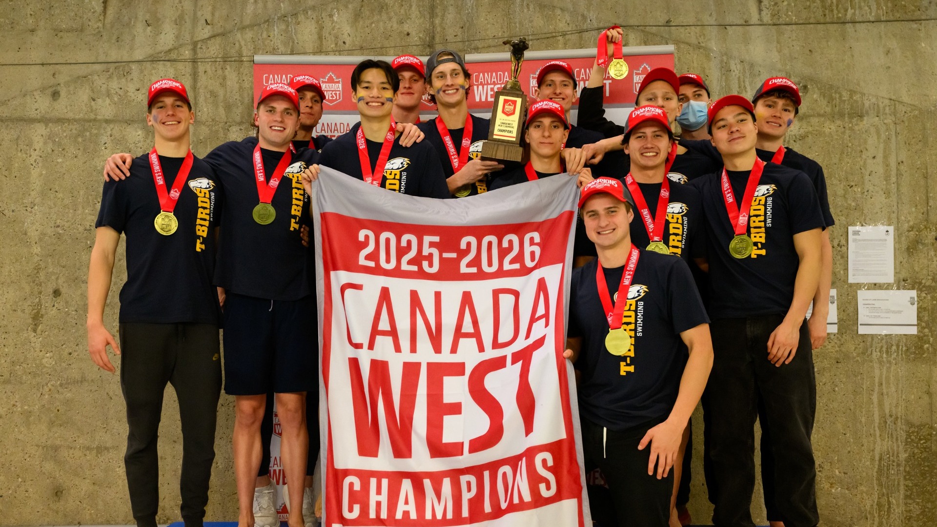 The UBC men's team poses with their 2025-26 Canada West Championship banner