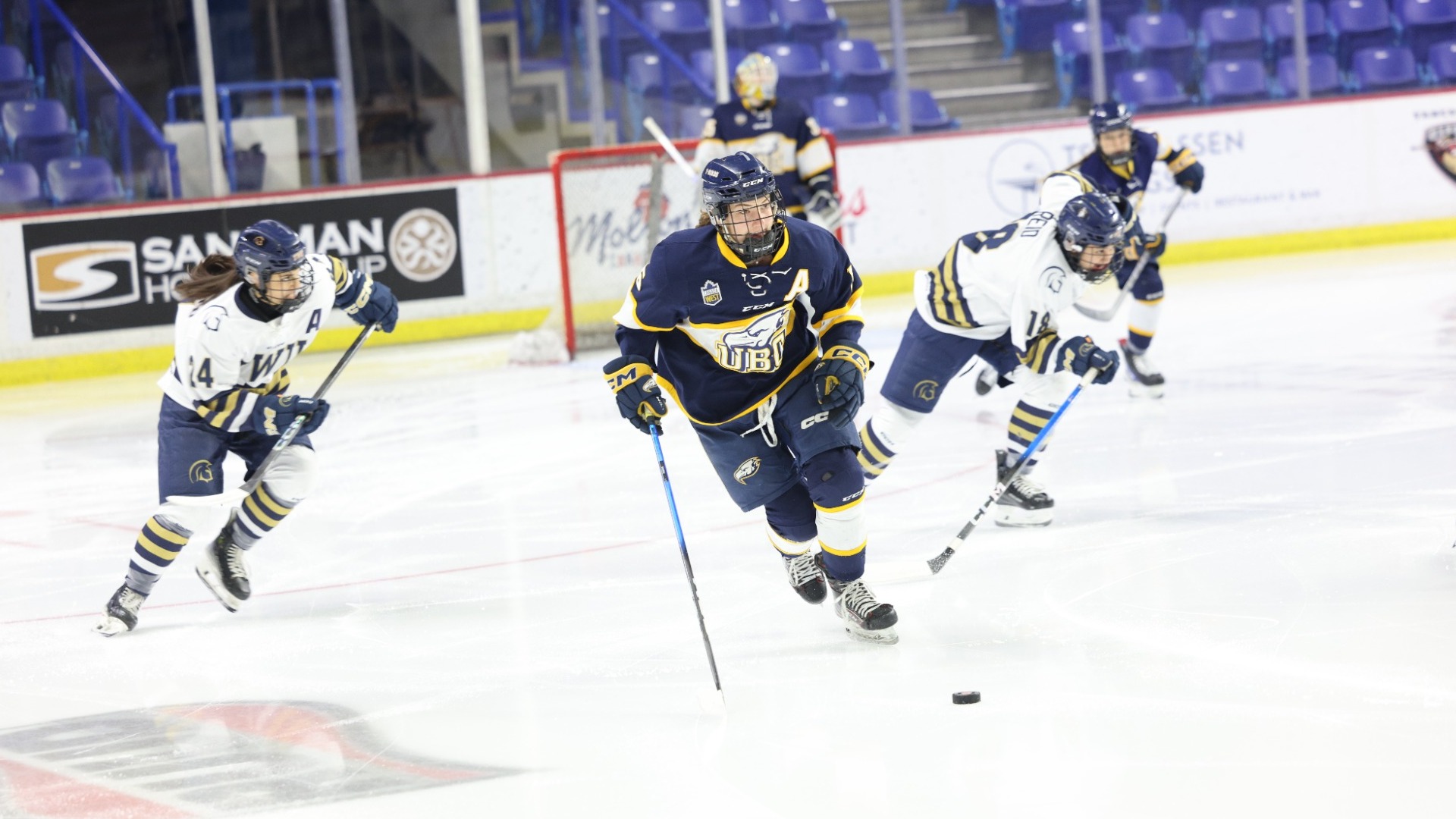 A UBC player carries the puck up the ice from their own zone