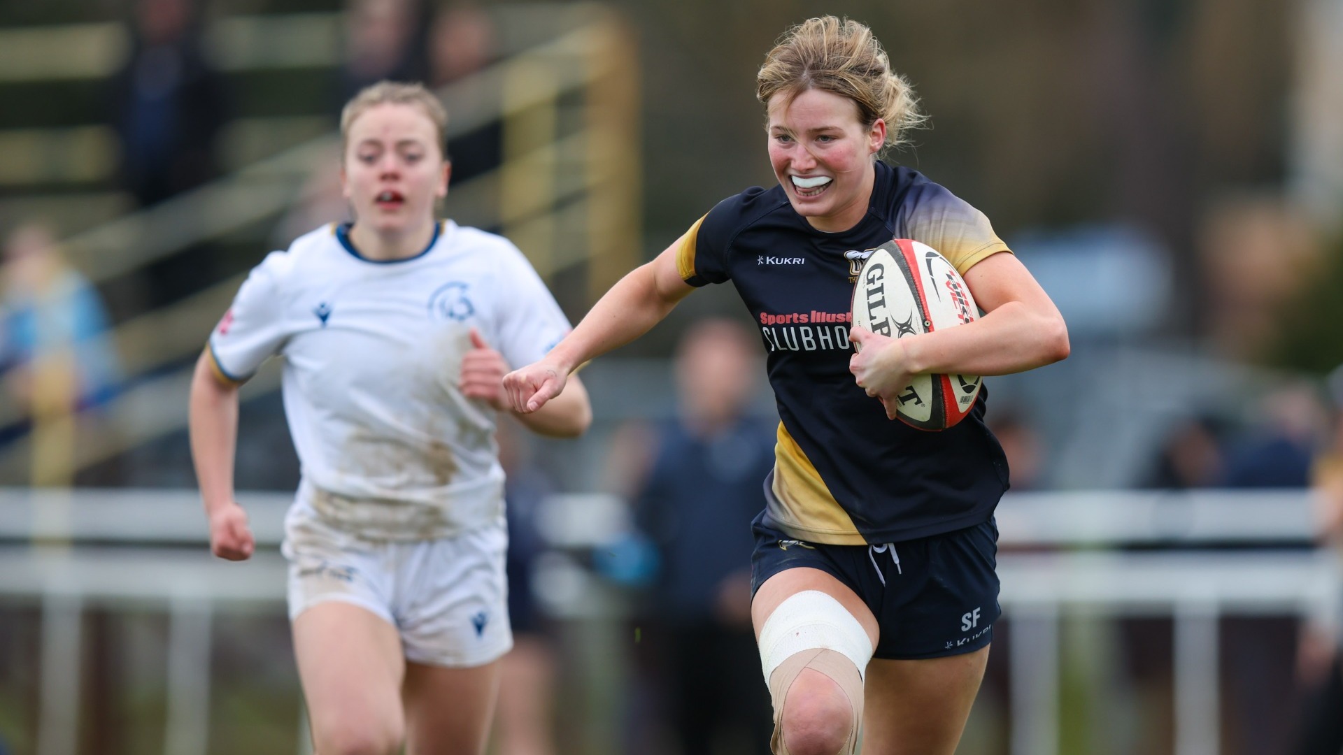 A UBC player grins as she runs forward with the ball