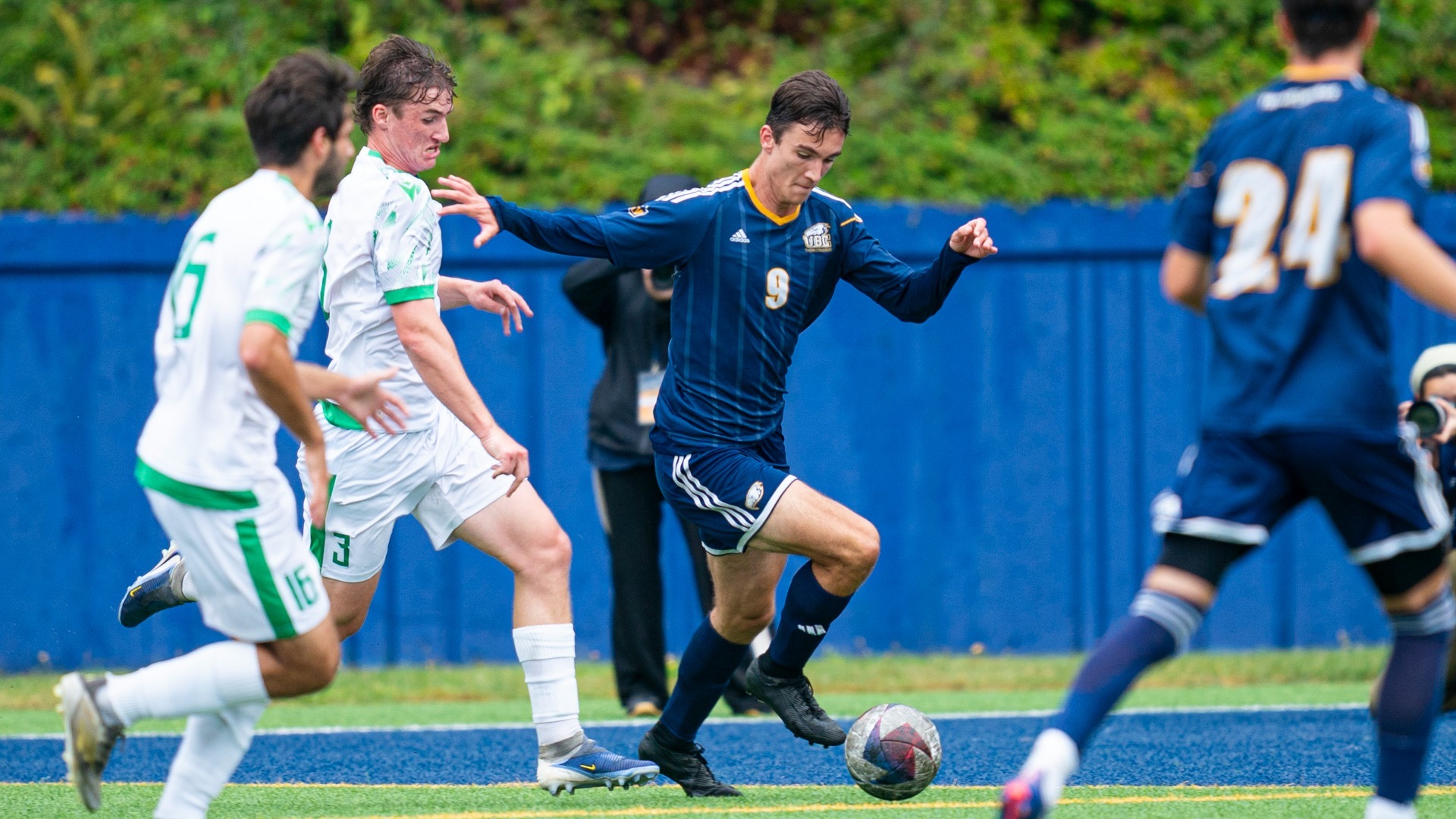 Max Comsia dribbles the ball while harried by a couple Huskies players