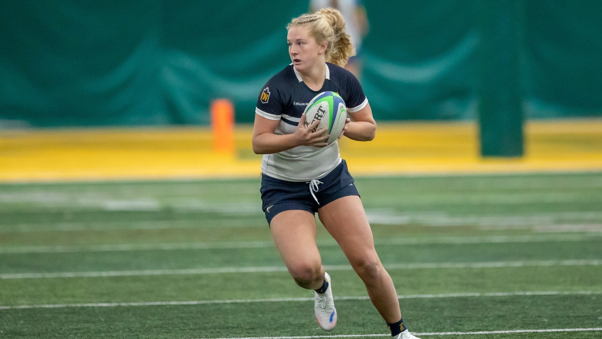 A UBC player runs with the ball while looking off to the side