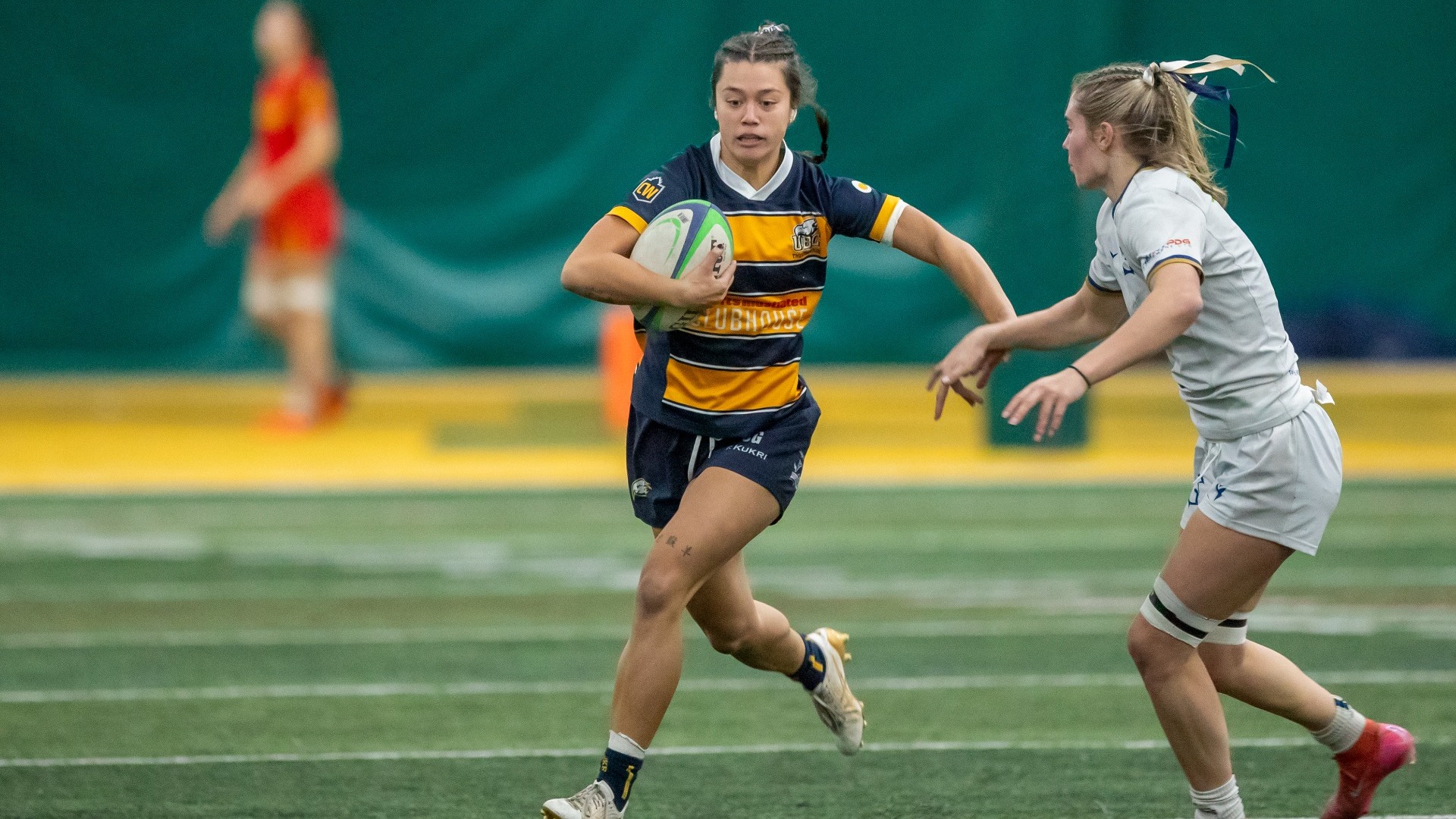 A UBC player runs with the ball with a defender running towards her