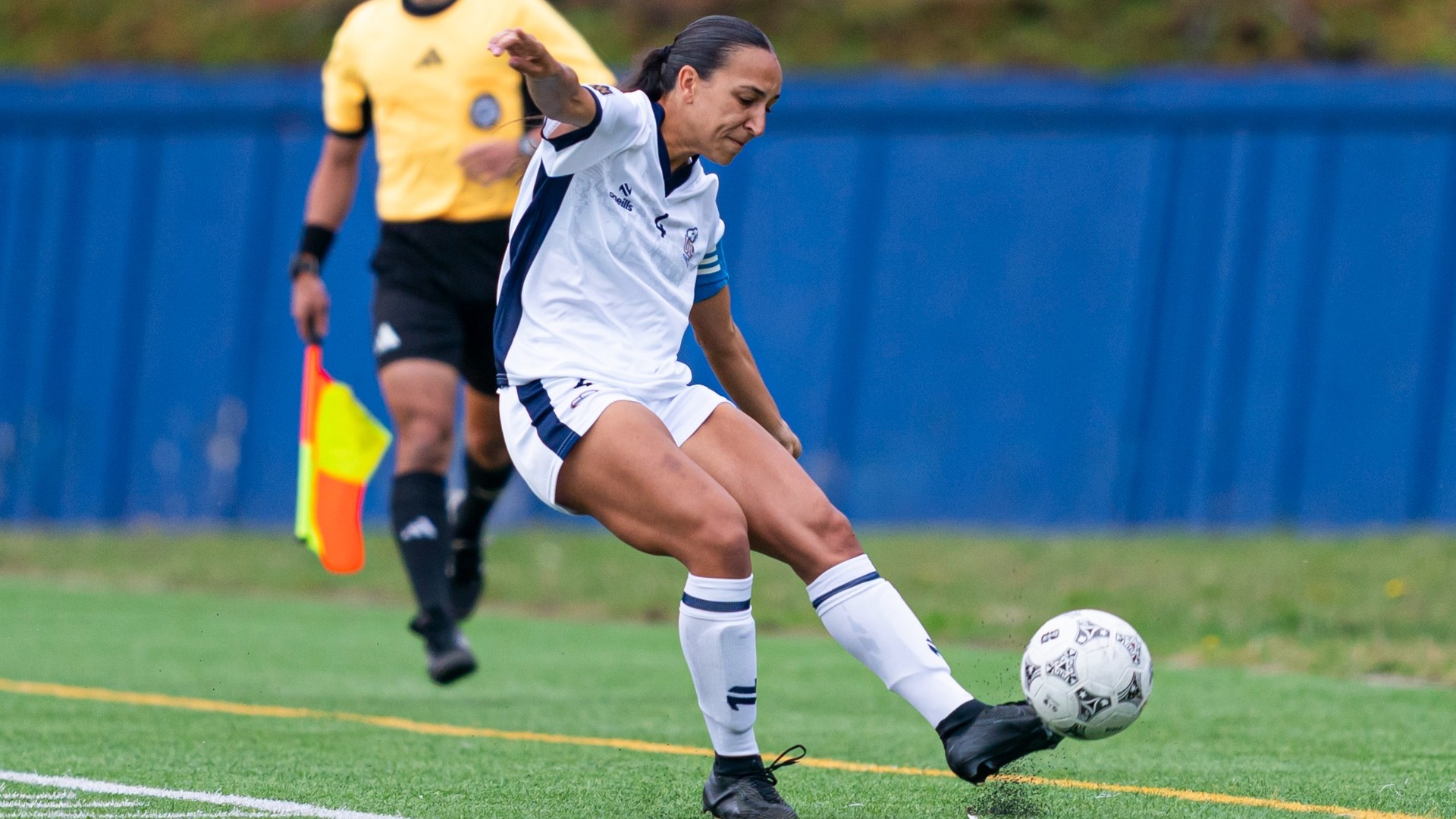 Sophia Ferreira is in the middle of kicking the ball down the sideline