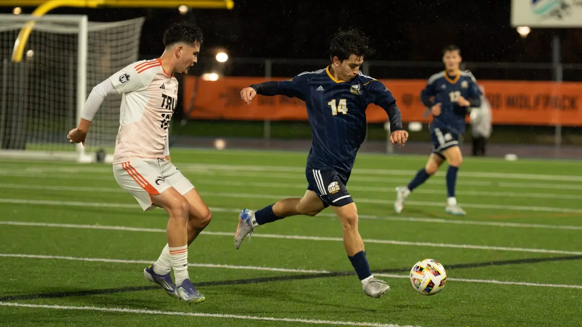 Oliver Herbert is about to kick the ball while pressured by a defender