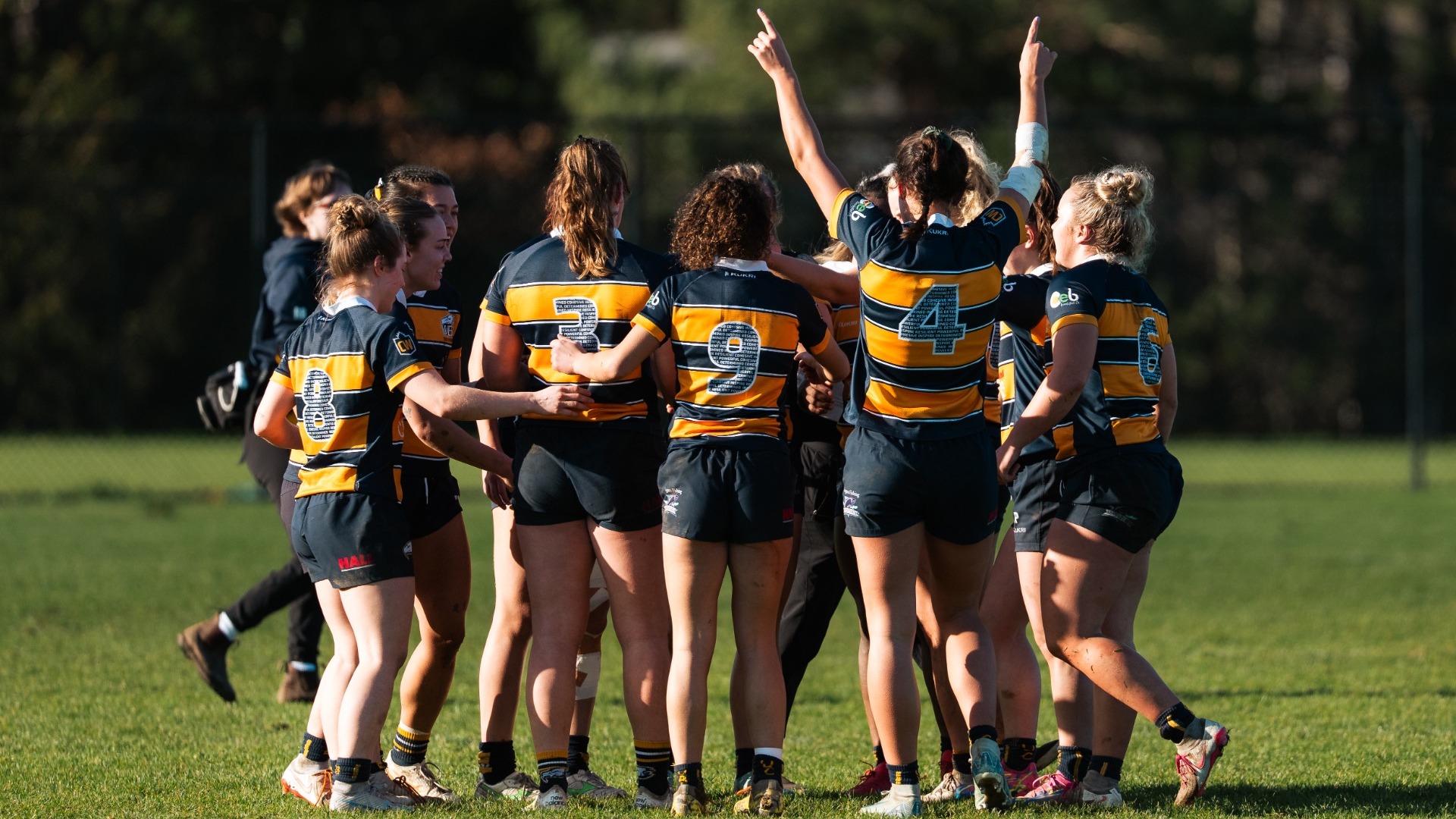 A group of UBC players huddle up after the match with their backs to the camera