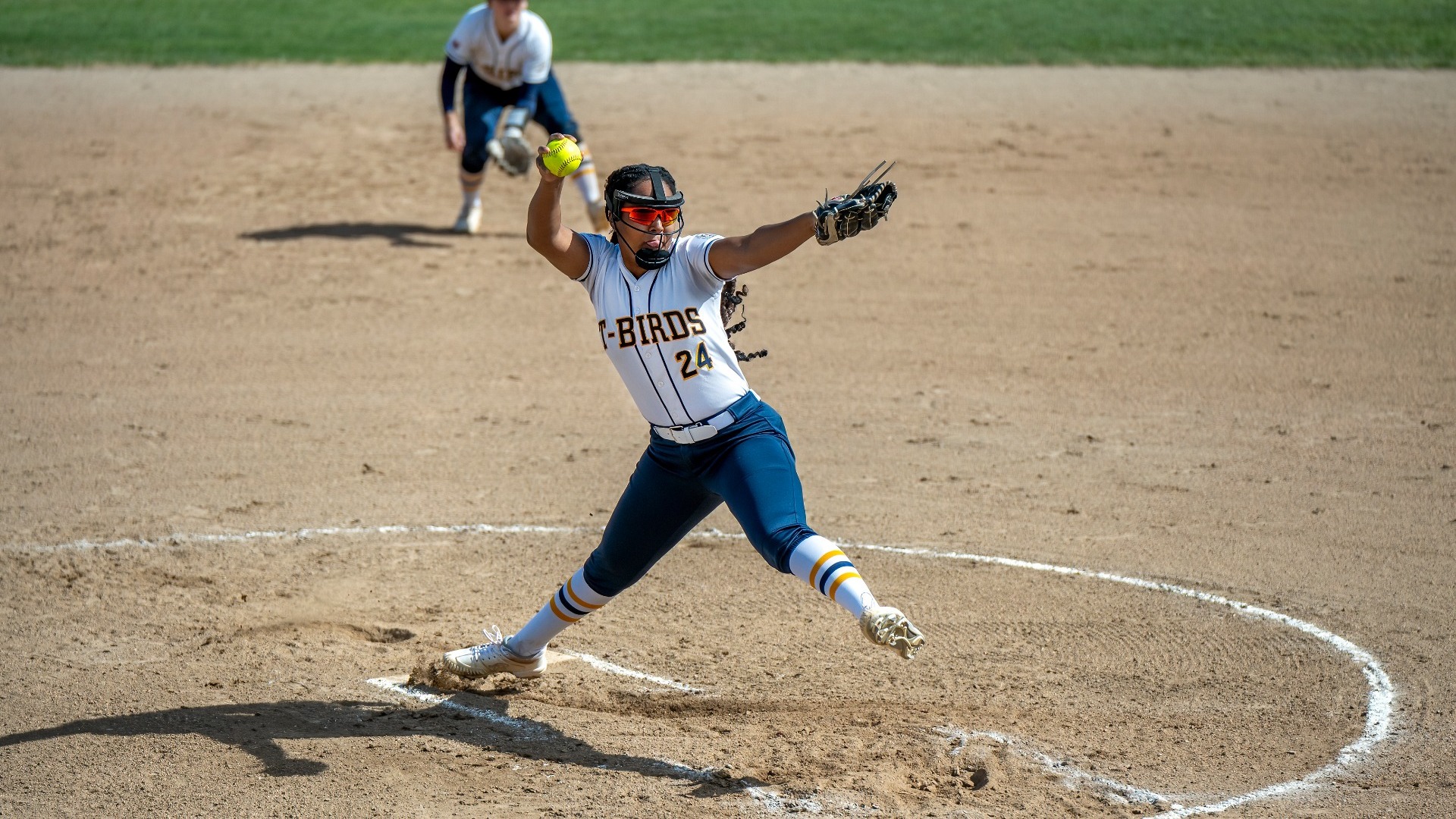 UBC pitcher Brynn Fortier seen from a high angle delivering a pitch, leg extended and arm whipping forward