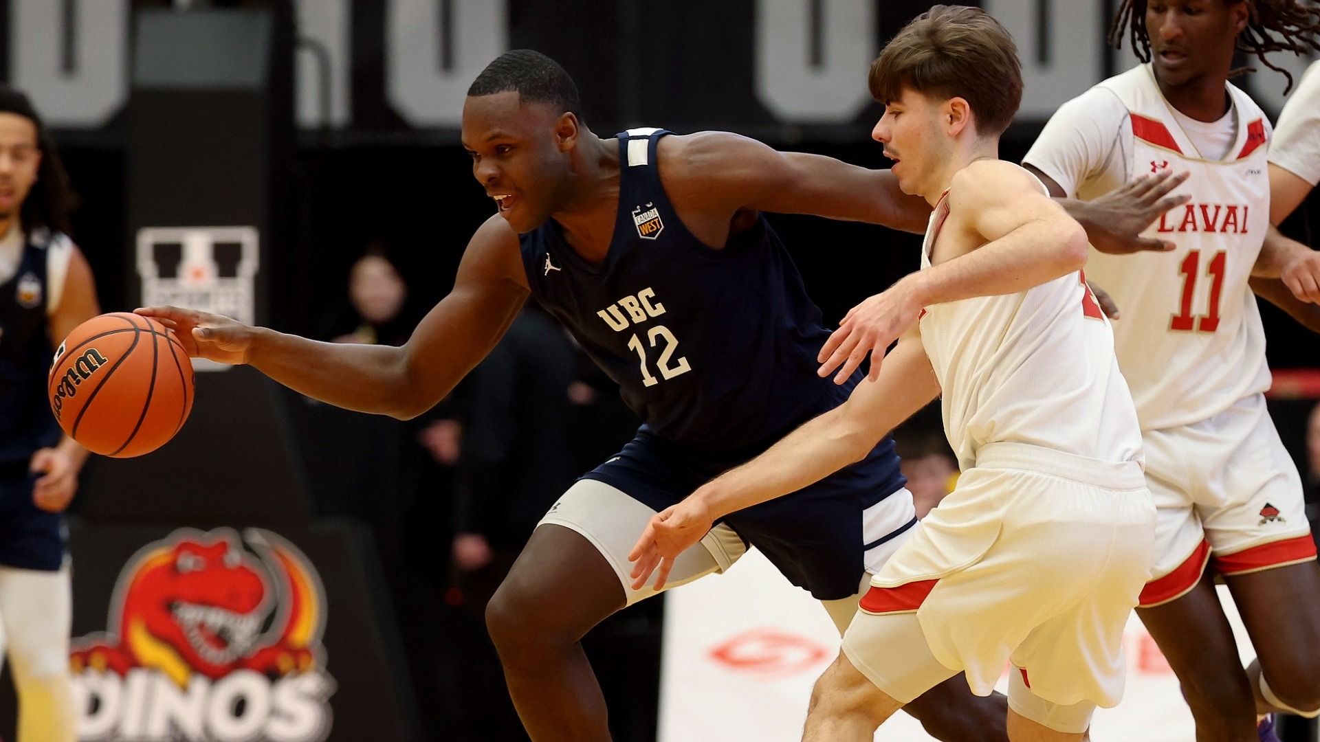 Kashie Ugoji with an excited expression, dribbling the ball with his right hand as he tries to escape a Laval defender