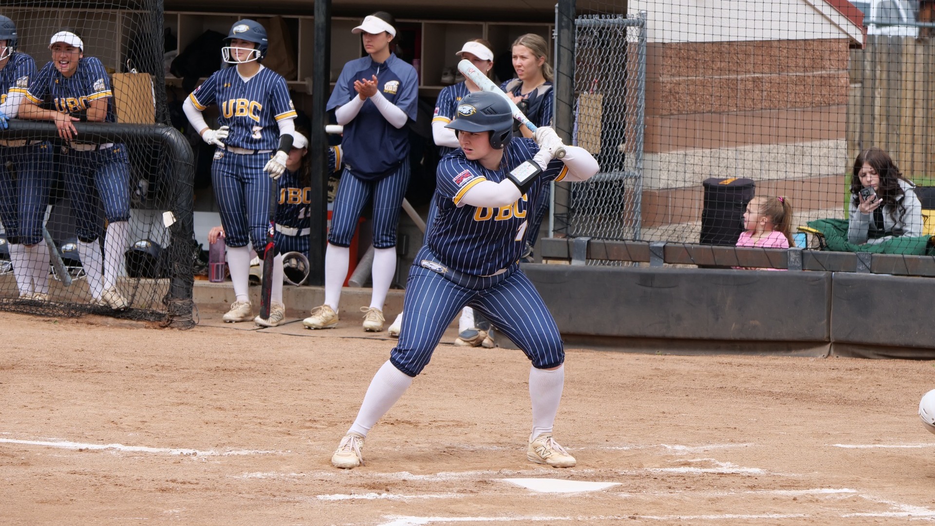 Jessica Heutink waits in the batters box for the pitch, while her teammates watch from the dugout behind her