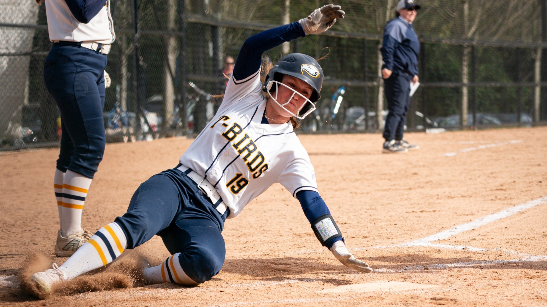 UBC outfielder Brielle Donoghue sliding into home, touching the plate with her left palm, still half off of the ground