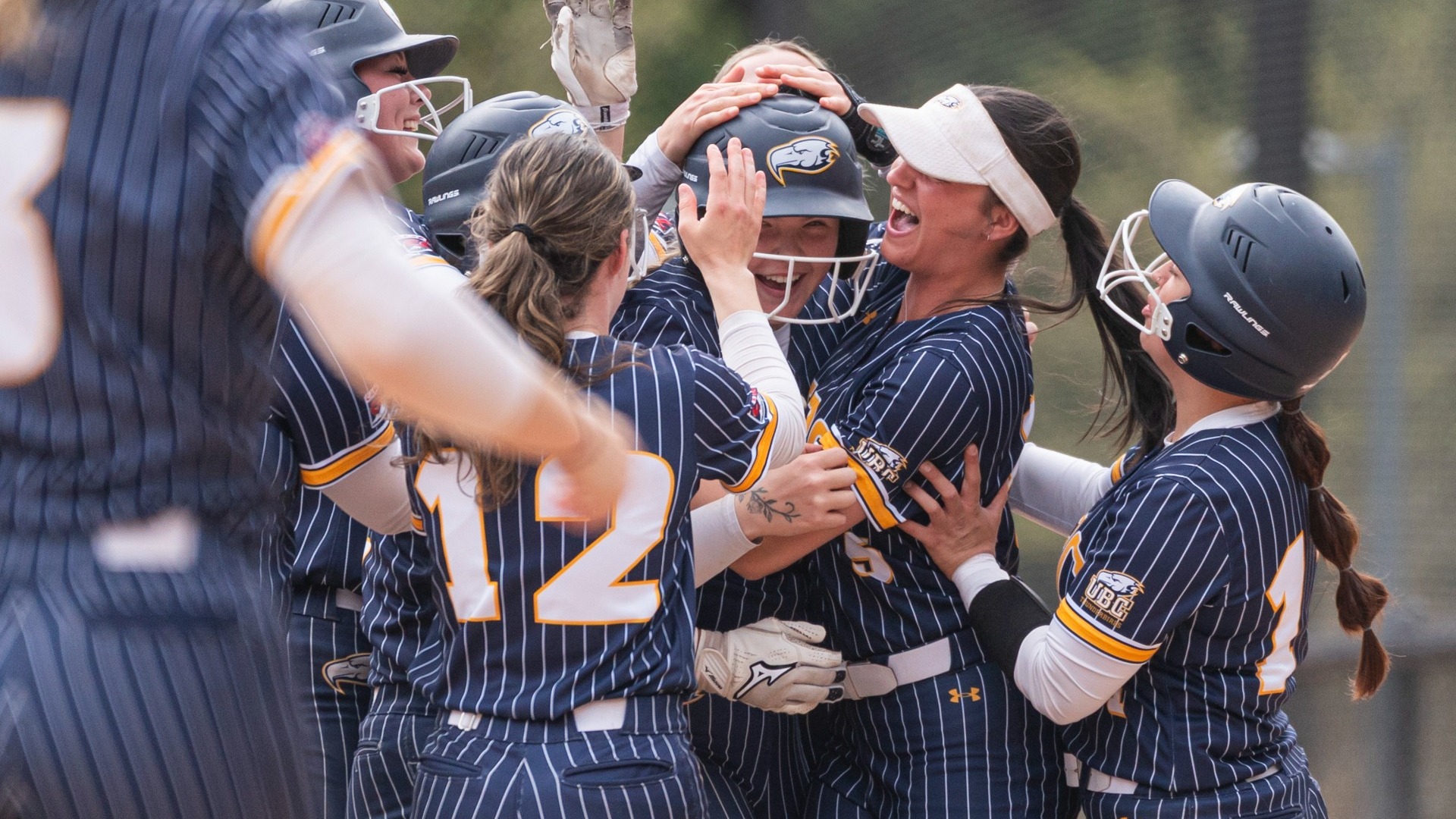 The UBC Thunderbirds softball team mobs shortstop Mattea Burrill, who's grinning after hitting a walk-off single to win the final game of the series against Warner Pacific
