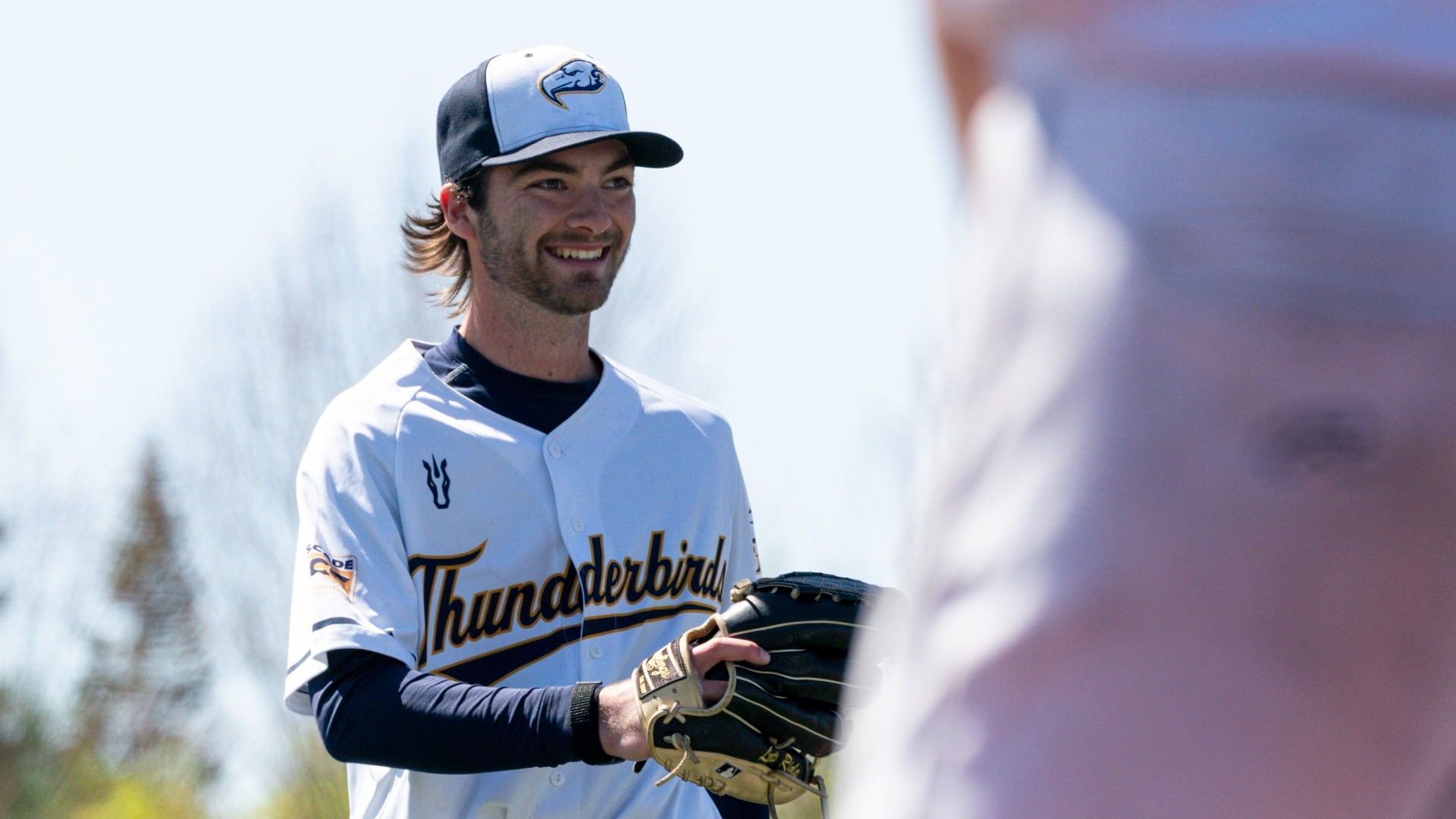UBC Thunderbirds relief pitcher Oliver Duthie grinning toward home plate before receiving the ball on the mound