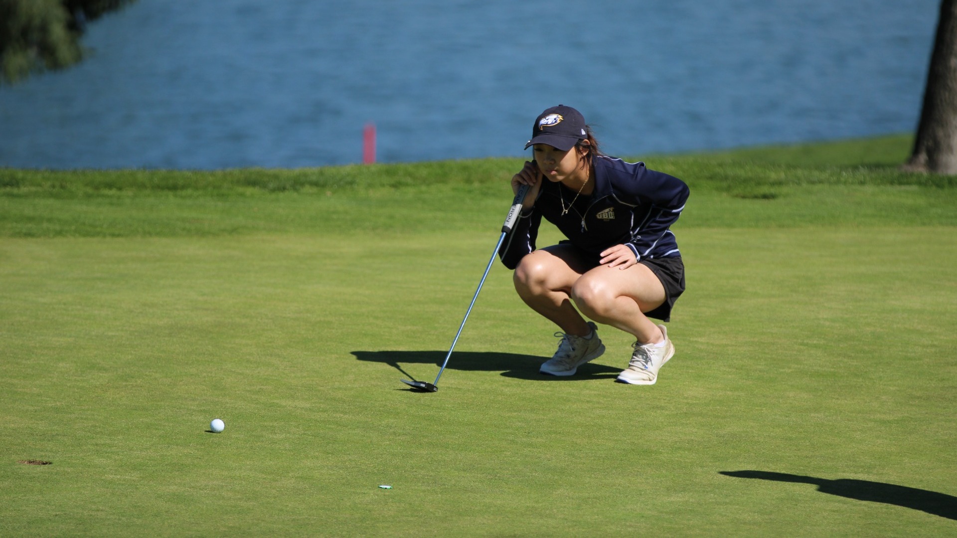 UBC Thunderbirds golfer Sarah Yang crouching down to size up a putt