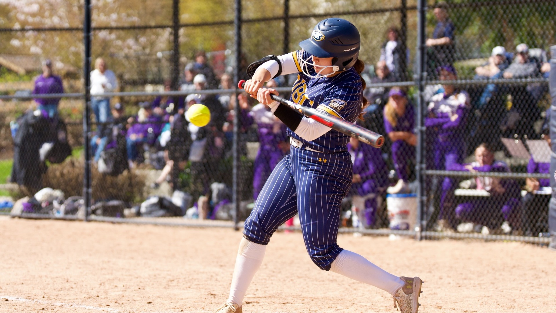 UBC infielder Clare VanSpall swinging at a pitch at the letters, her bat appearing to be on the same plane as the ball and a fraction of a second from making contact as it comes in, half a meter away