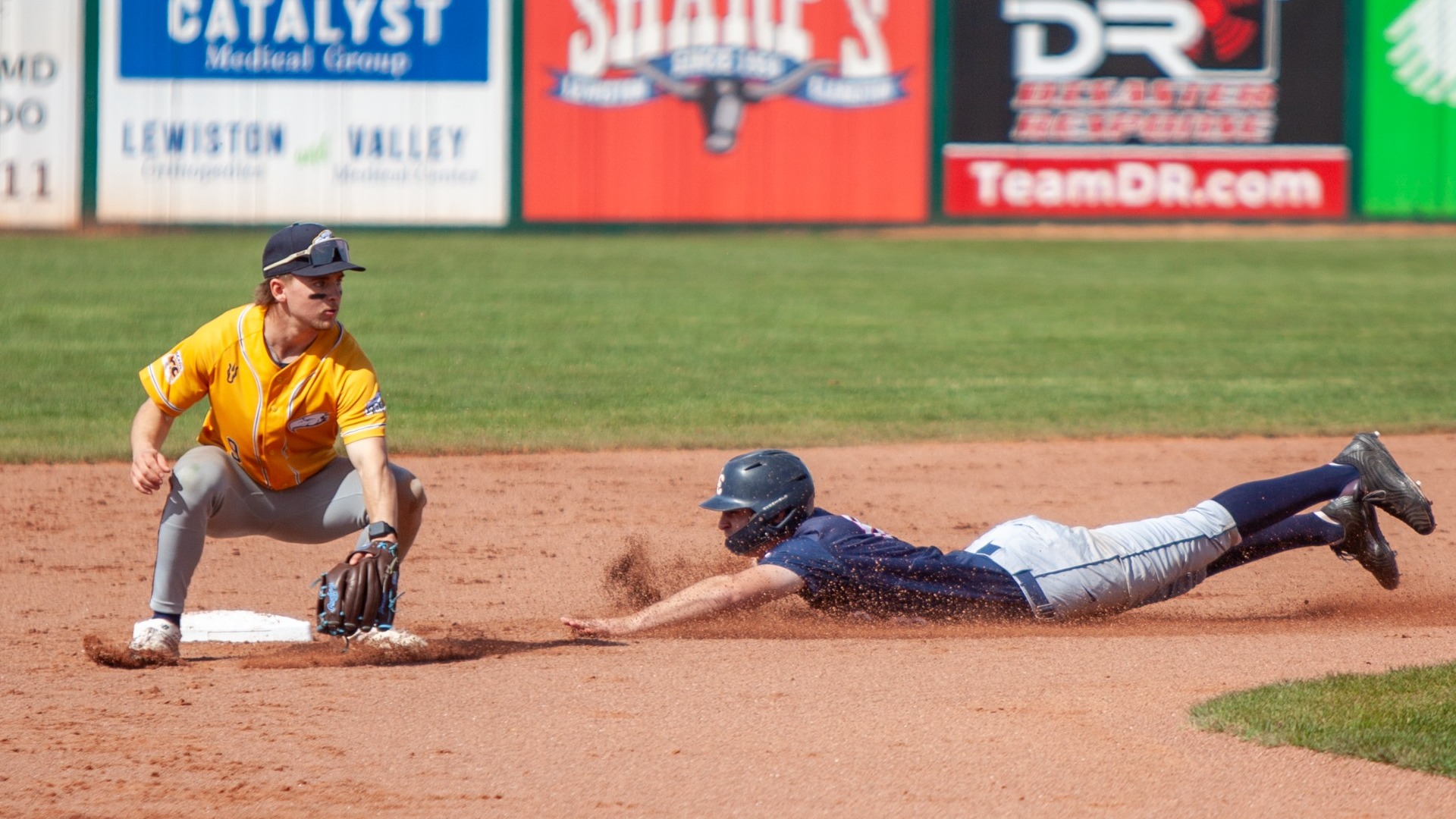 Matt Vrlak crouches down at second base while a Lewis-Clark baserunner slides head-first towards it