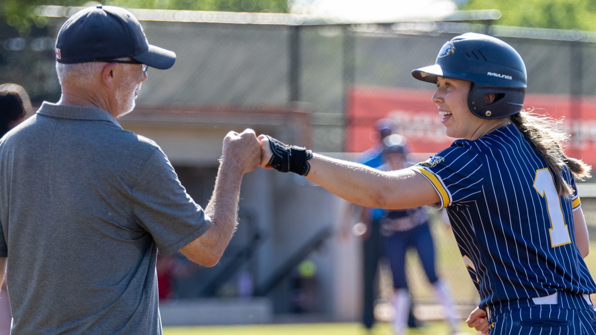 Kennedy Laird fist bumps the UBC first base coach after getting on base