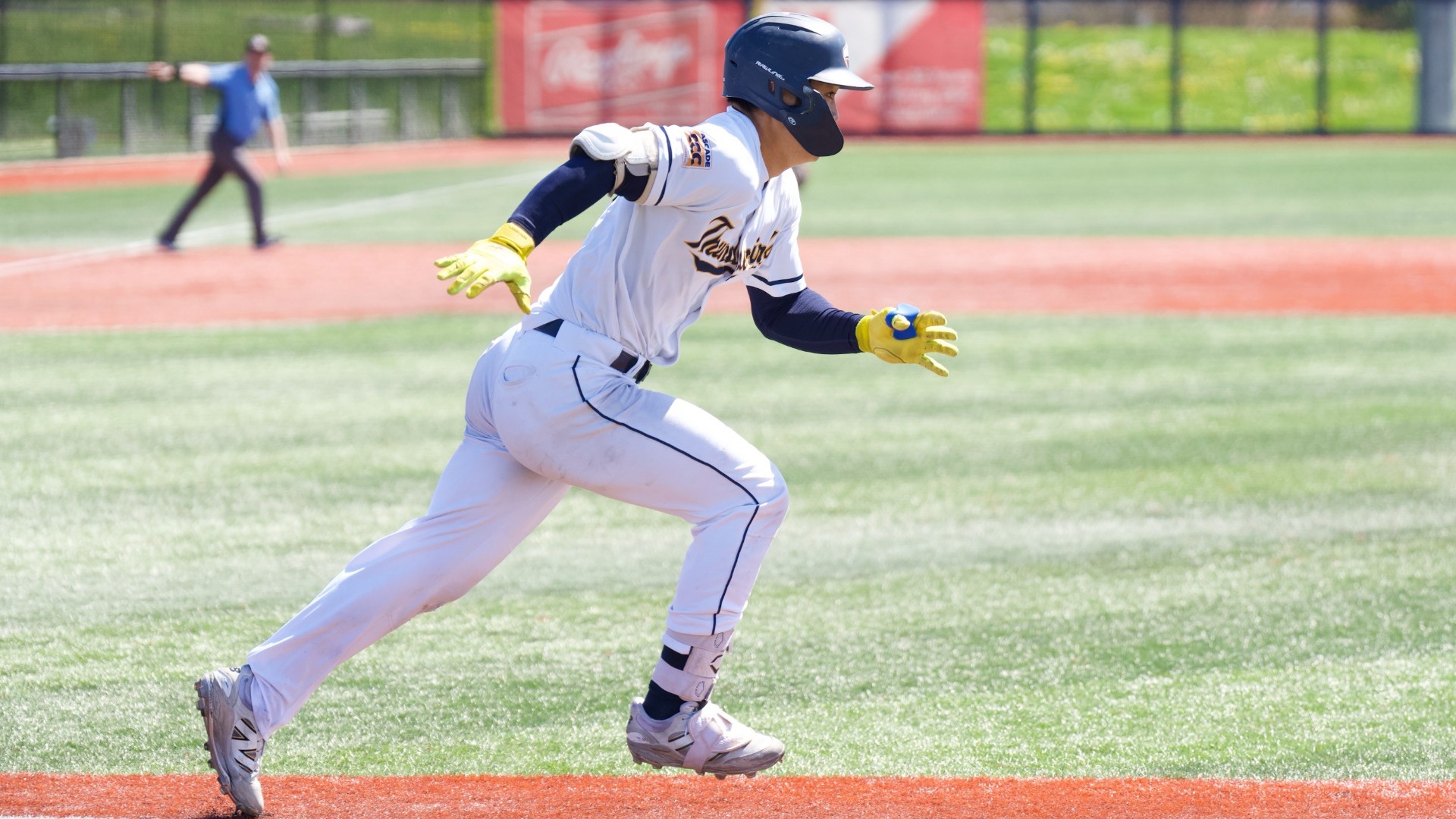 A UBC player runs down the first base line after hitting the ball