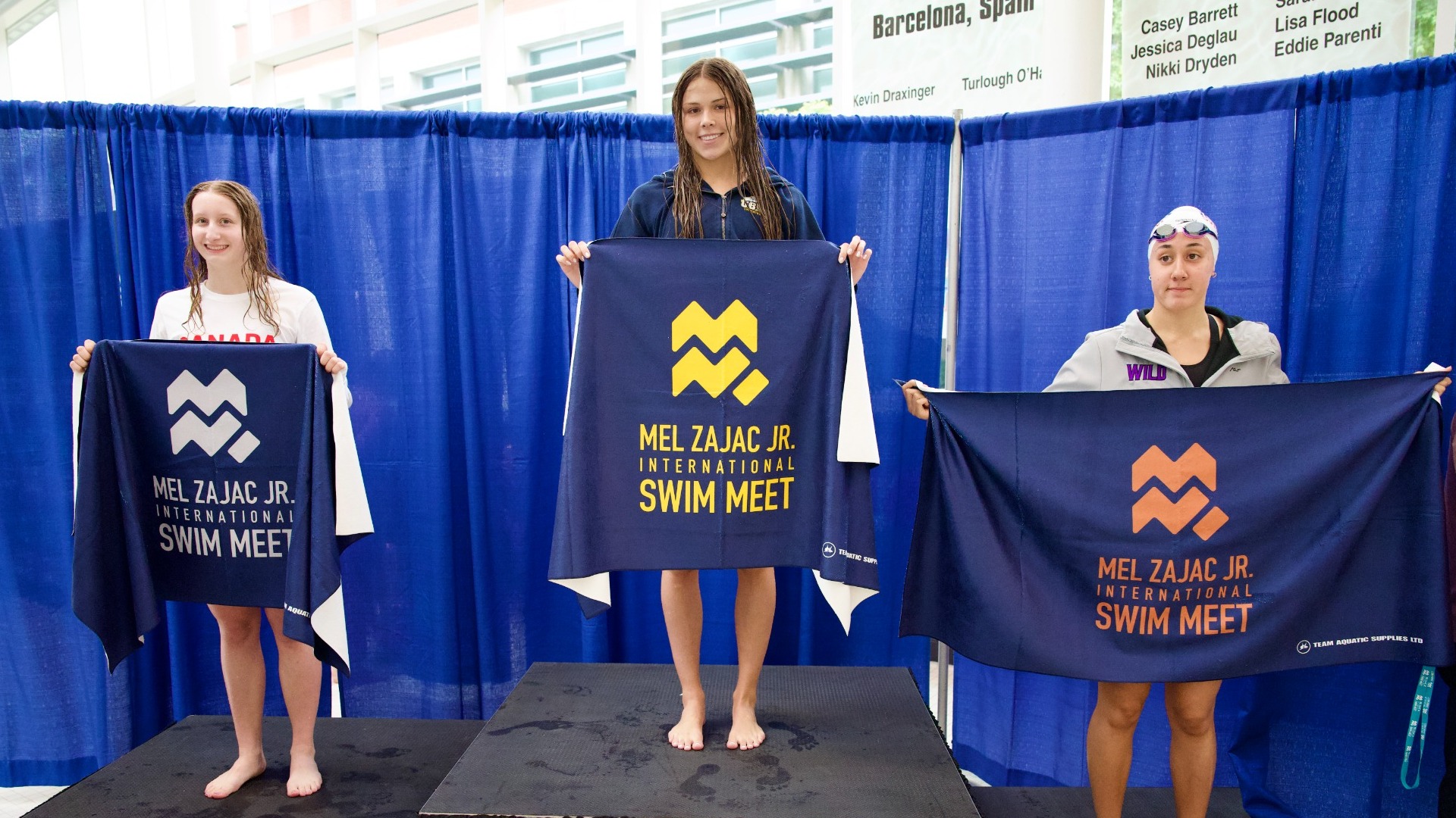 UBC Thunderbirds swimmer Eloise Allen smiles and holds a gold banner atop the podium after winning the 100 meter breastroke A Final at the 61st Mel Zajac Jr. International Swim Meet