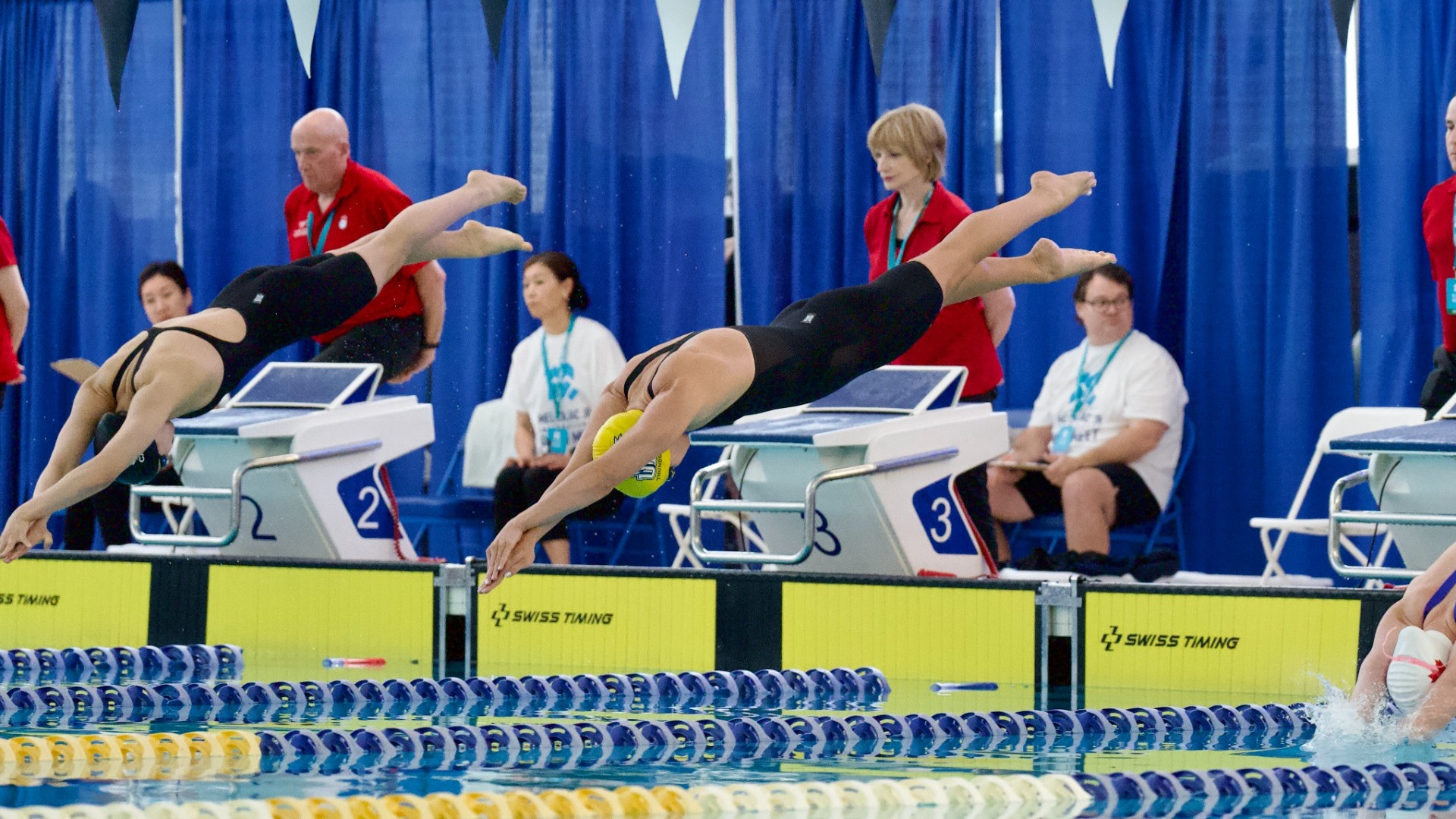 A UBC Thunderbirds women's swimmer dives headfirst into the pool at the start of a race