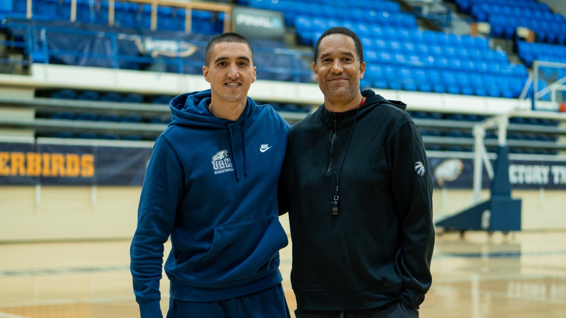UBC Thunderbirds head coach Phil Jalalpoor smiles and poses with UBC basketball alumnus and Toronto Raptors assistant coach Jama Mahlalela on the floor of War Memorial Gym