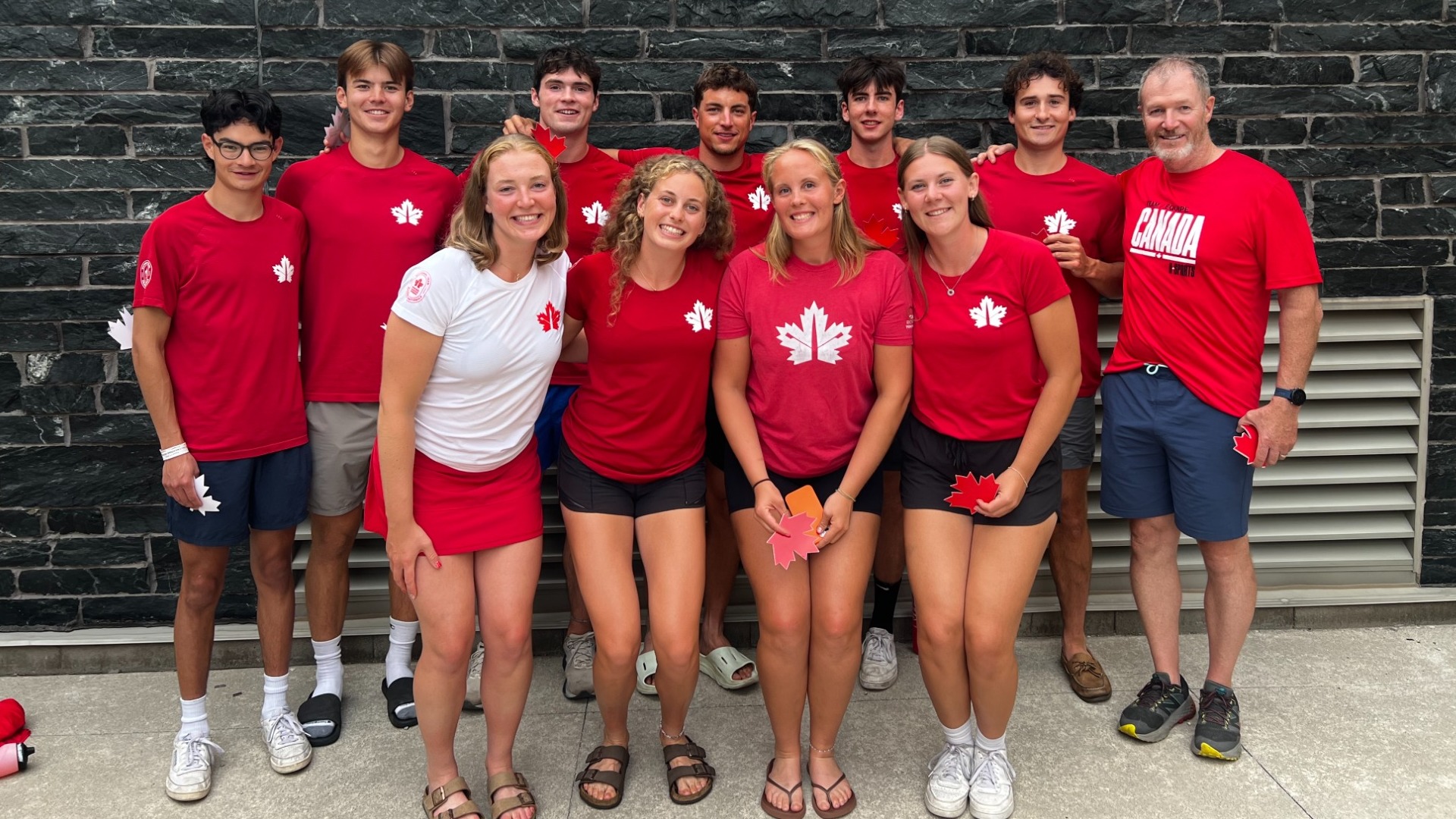 A group of Thunderbirds and coach Mike Pearce pose together for a picture at 2026 FISU Rowing Championships