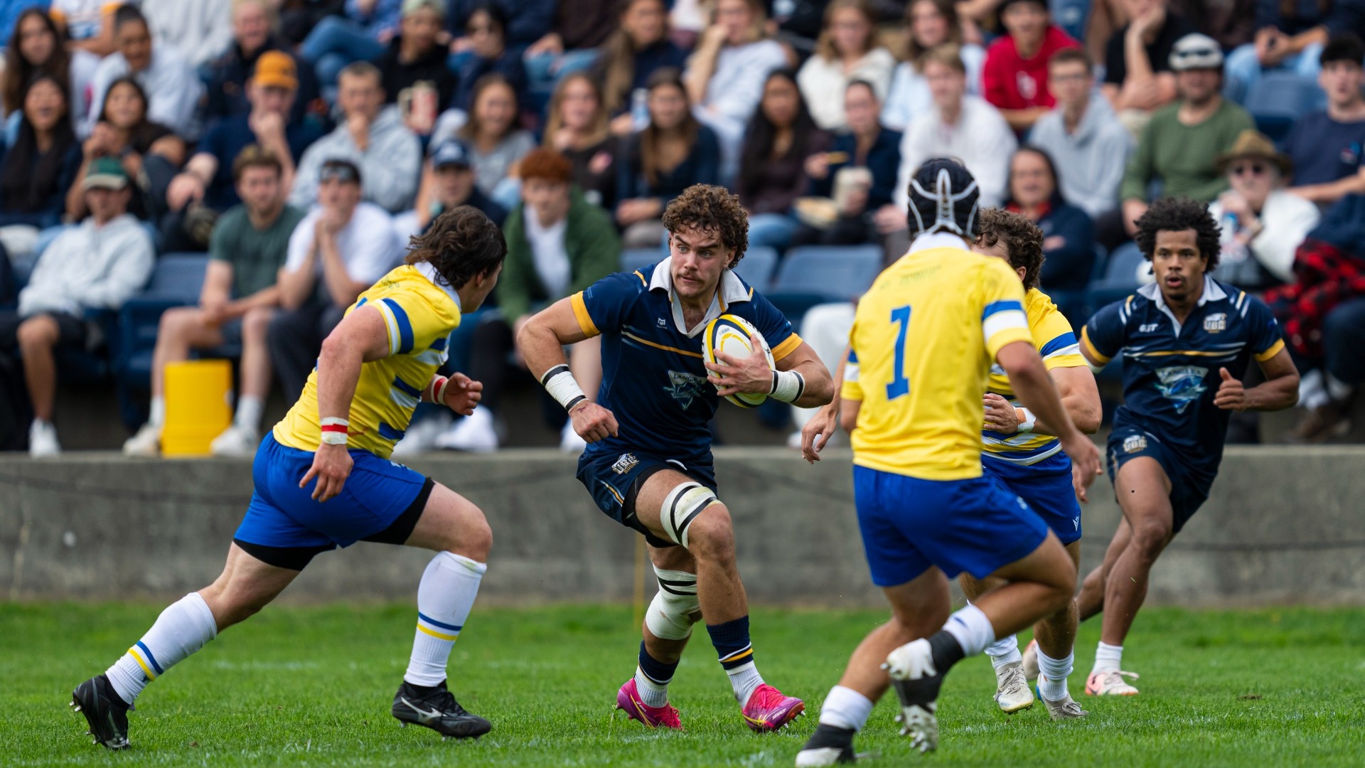 A UBC T-Bird runs with the ball while trying to avoid incoming defenders against the UVic Vikes on Sept. 12, 2026.