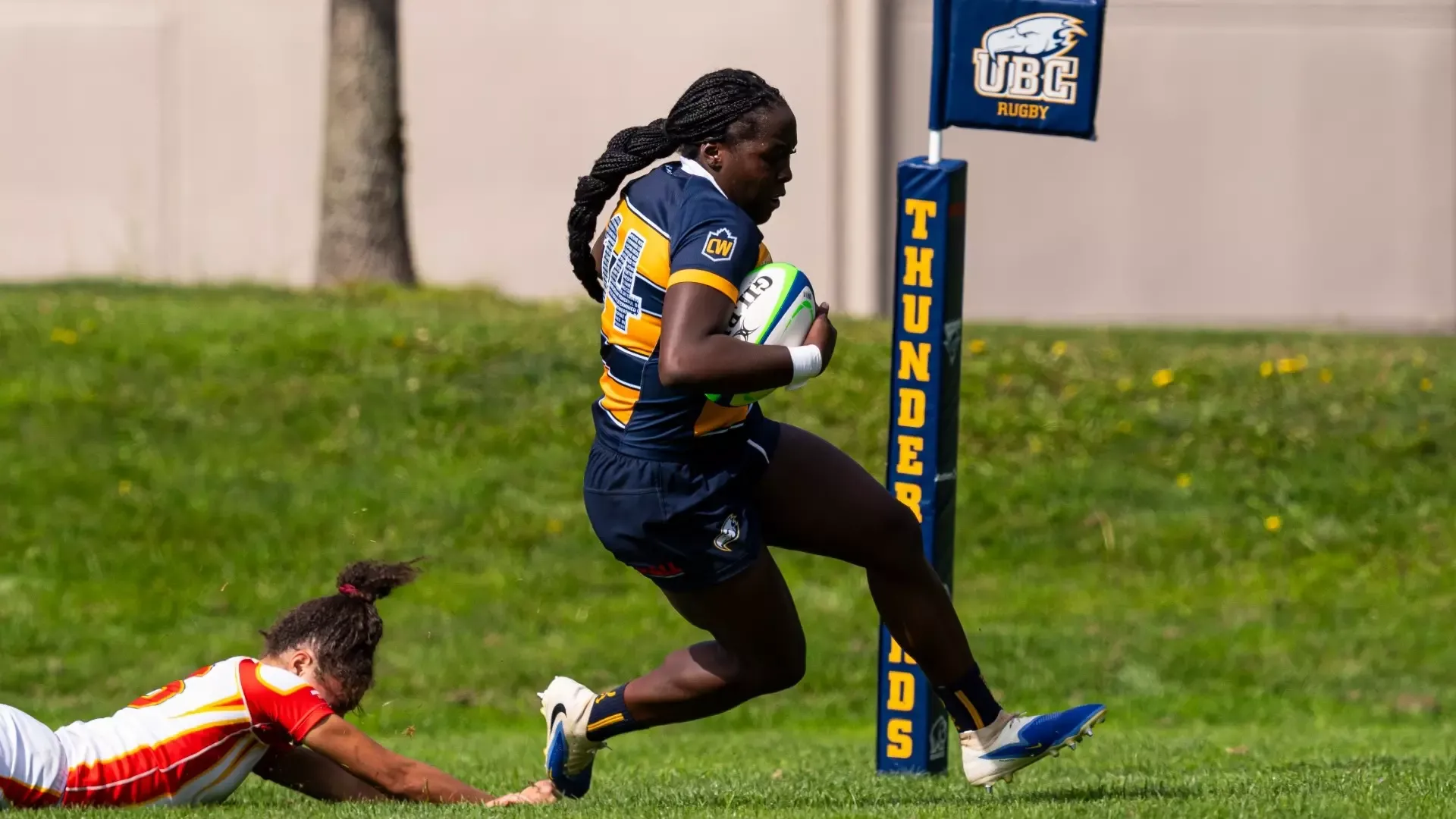 UBC's Teniola Epemolu scores a try while a defender falls just short behind her during a game against the University of Calgary Dinos on Sep. 19, 2026
