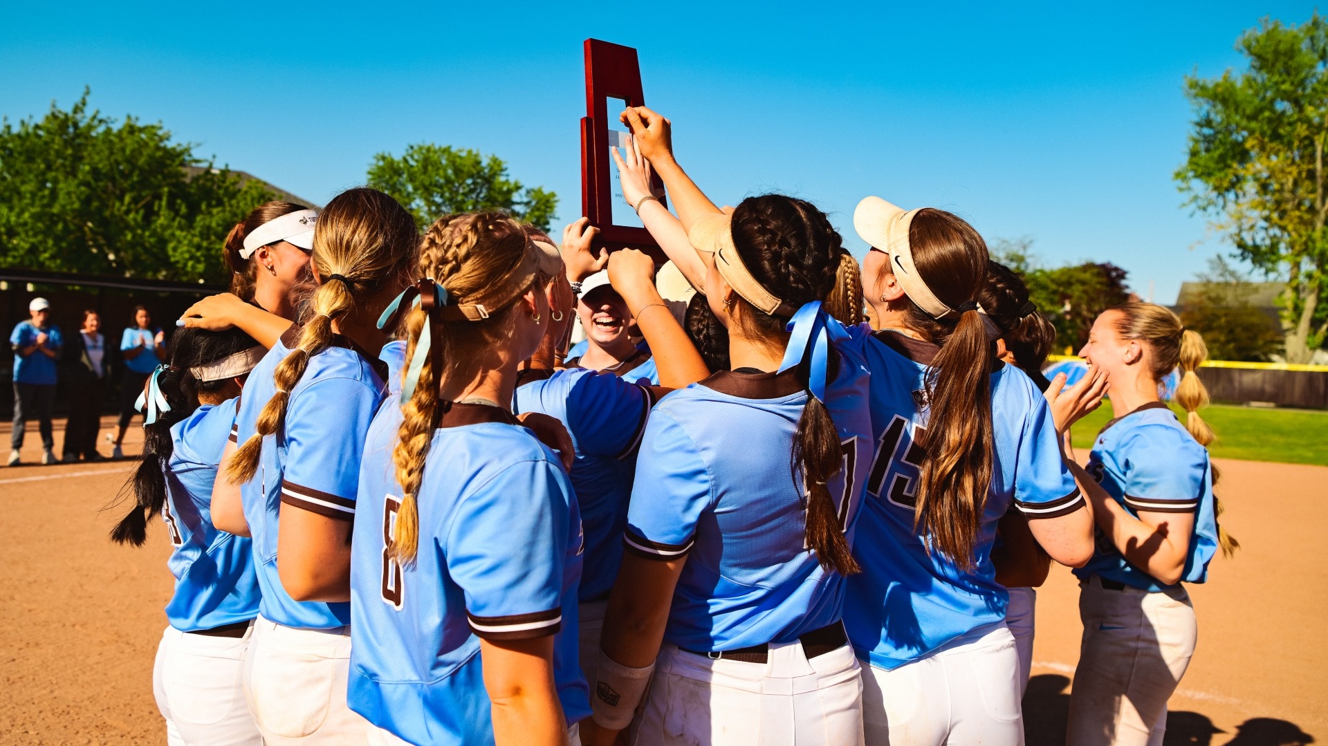 The 2025 Tufts softball team celebrates with the NESCAC trophy.