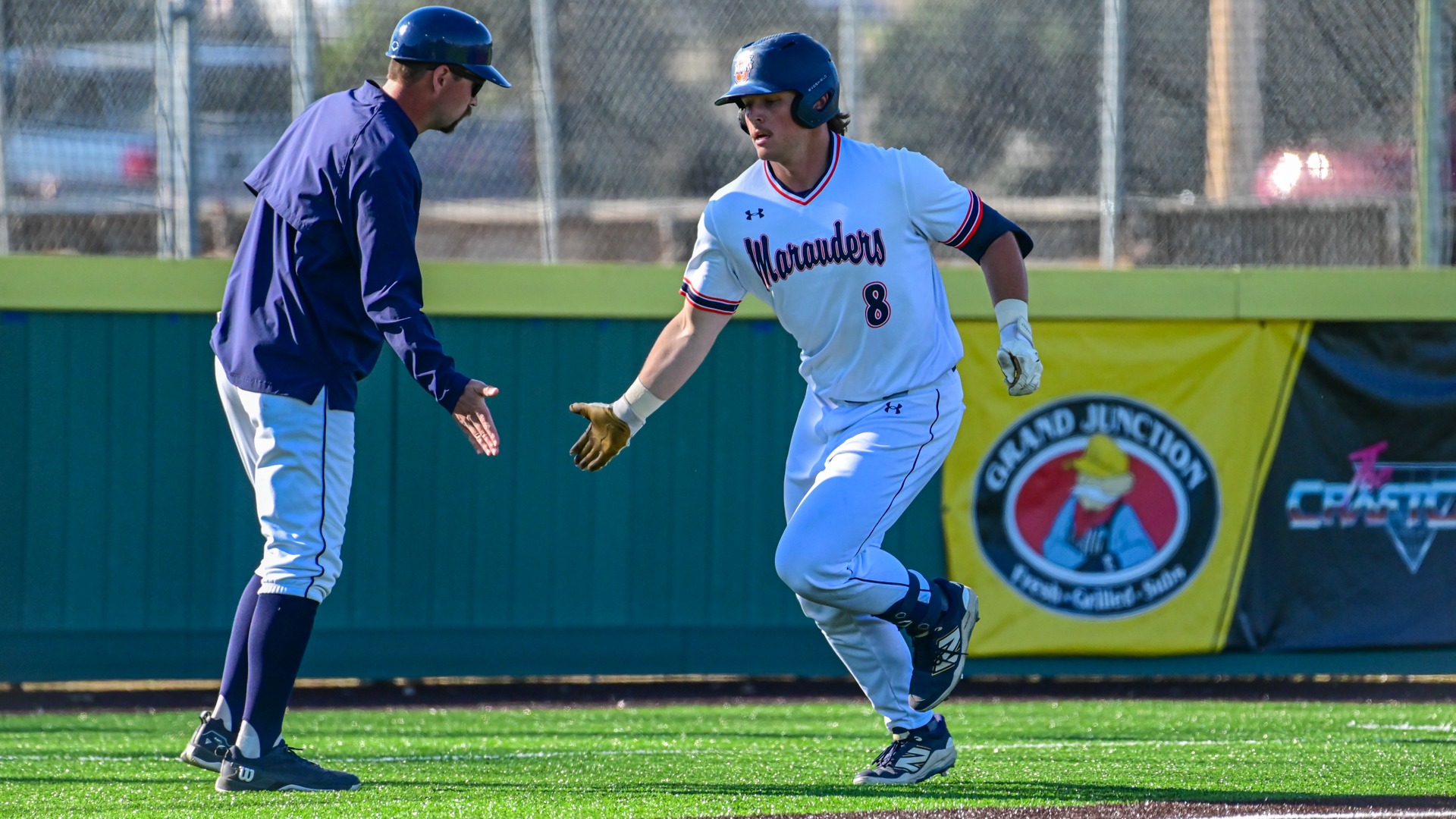 Isaac Pegors celebrates with coach Tyrus Barkley while rounding third base