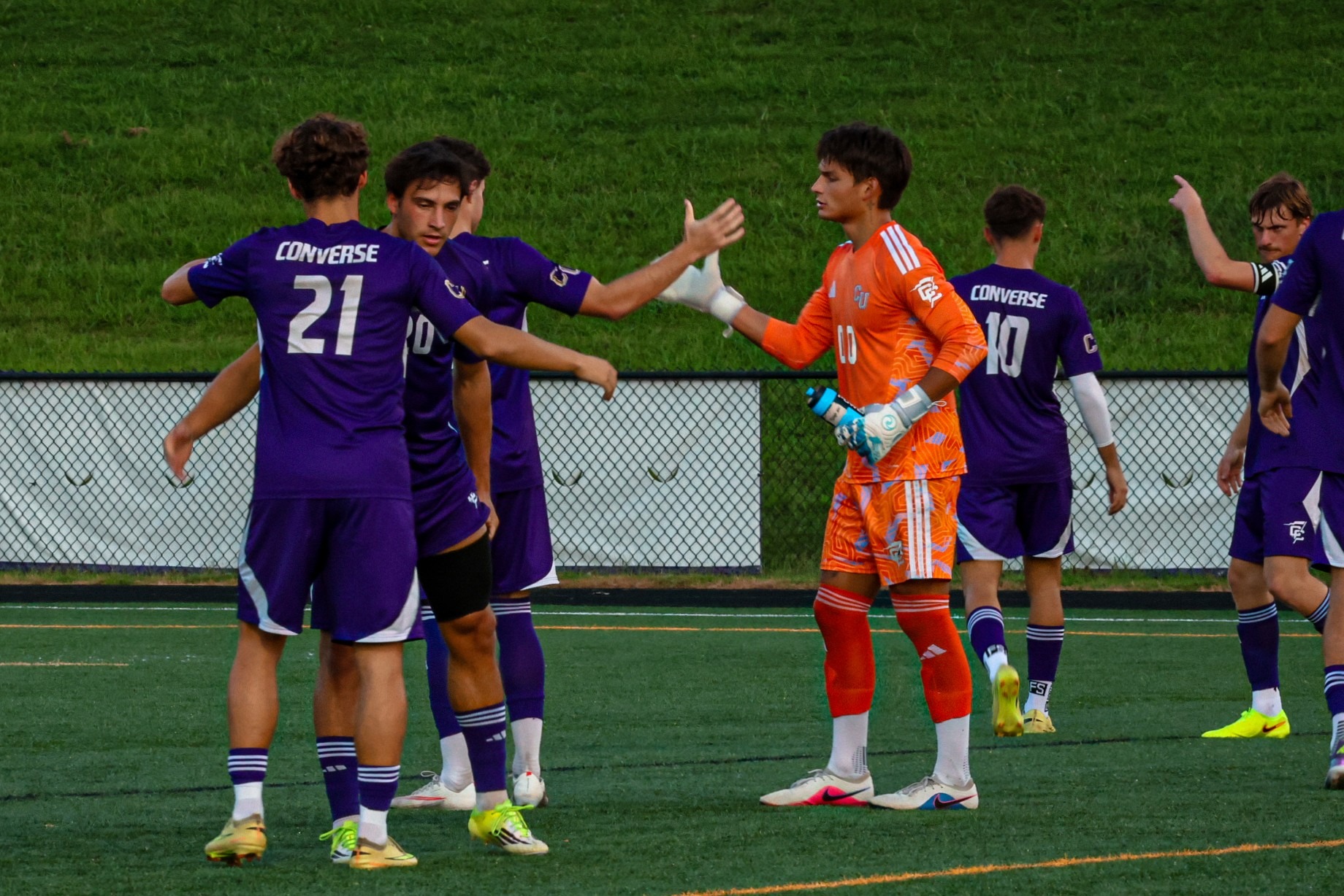 Several men's soccer players high five prior to a game