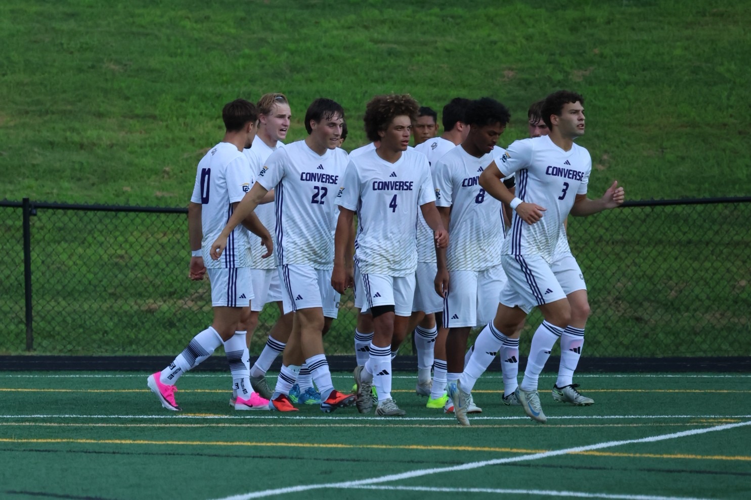The Converse men's soccer team celebrates a goal on the field
