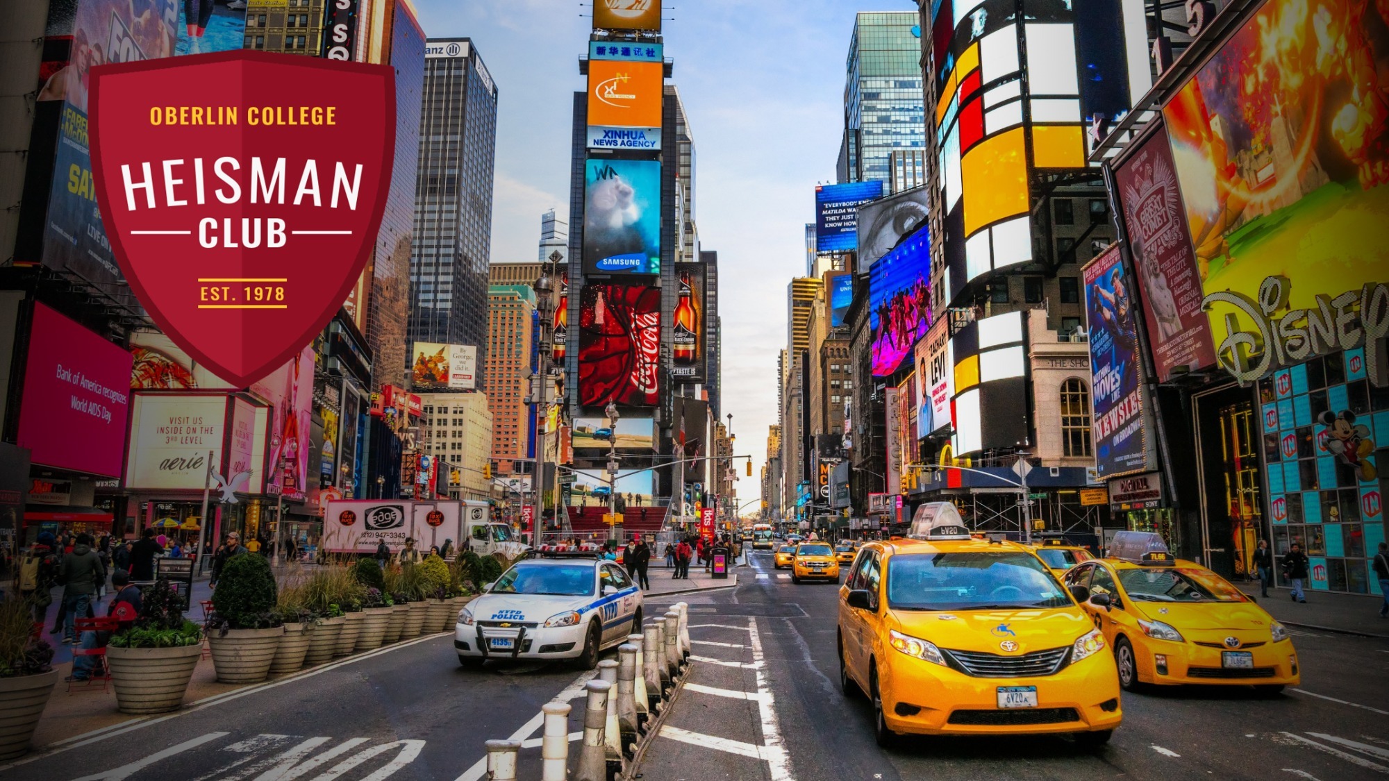 Image of Times Square in NYC with Heisman Club Shield in upper left corner