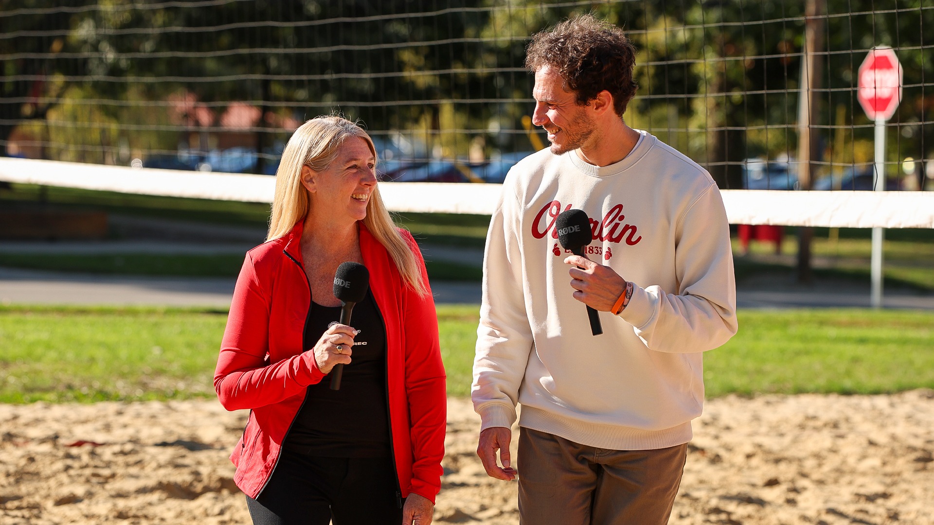 Christine Varga and Ben Wach smiling while walking on the sand volleyball courts