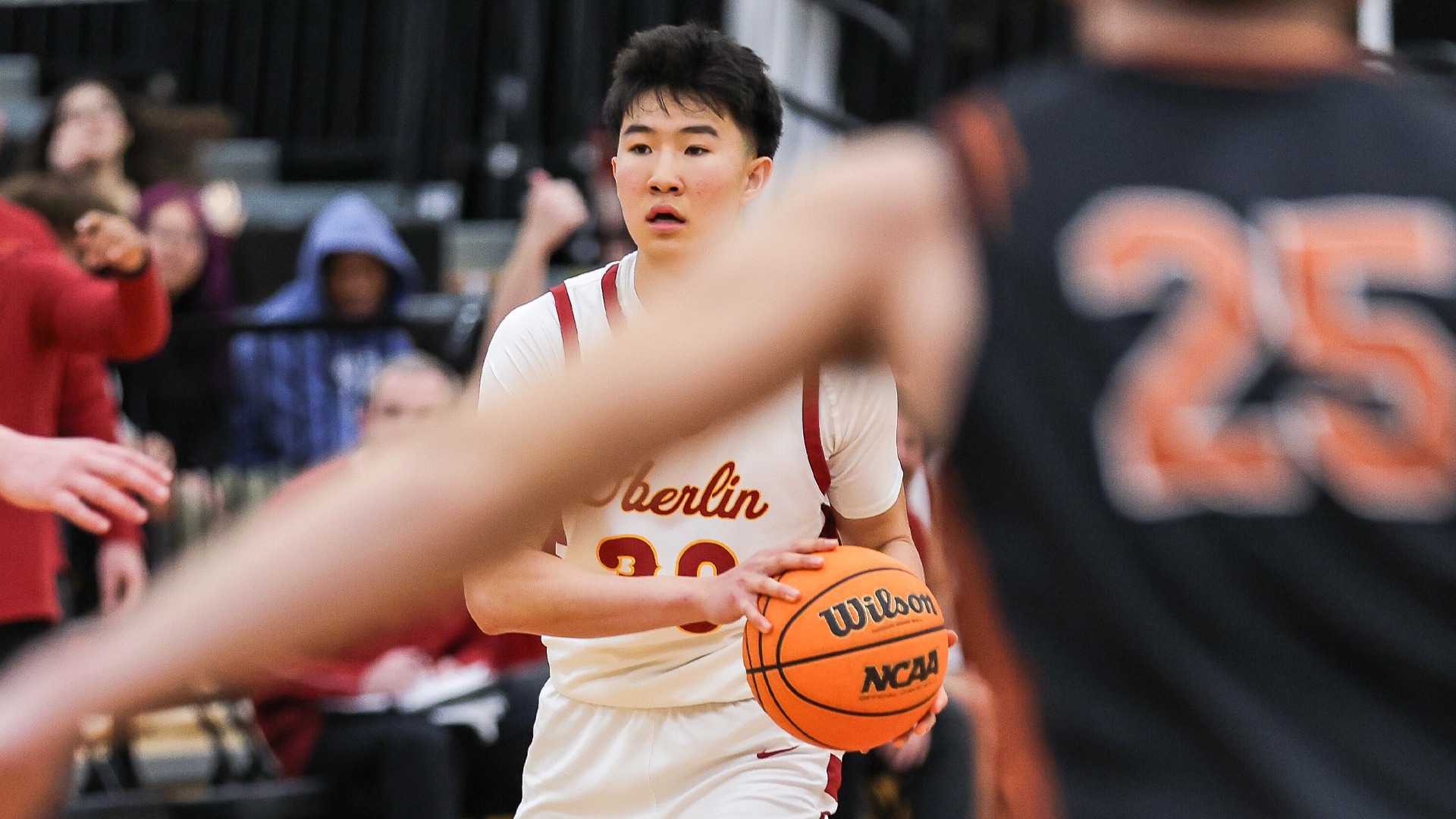 Noah Kim with basketball looking at team