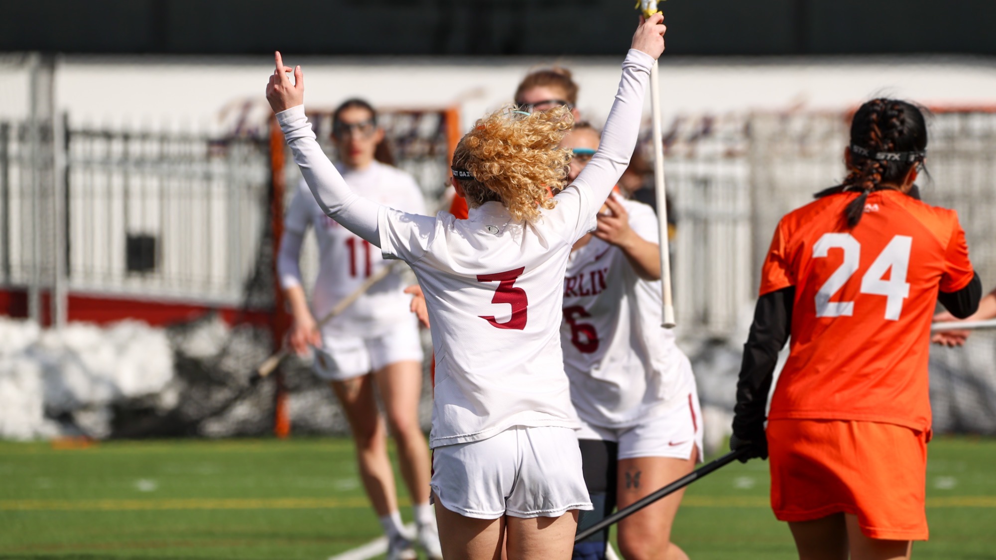 Megan Hiller with her back turned and arms in the air celebrating a goal