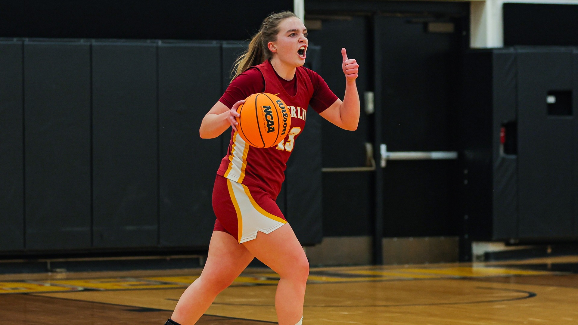 Lily Najmulski dribbles the ball while holding a thumbs up with her left hand
