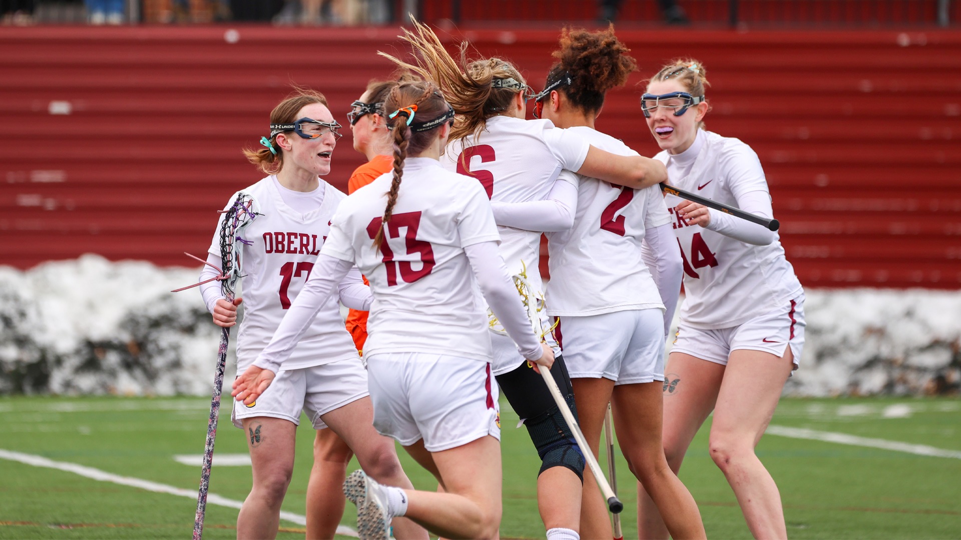 Women's lacrosse team celebrates in a huddle after scoring a goal