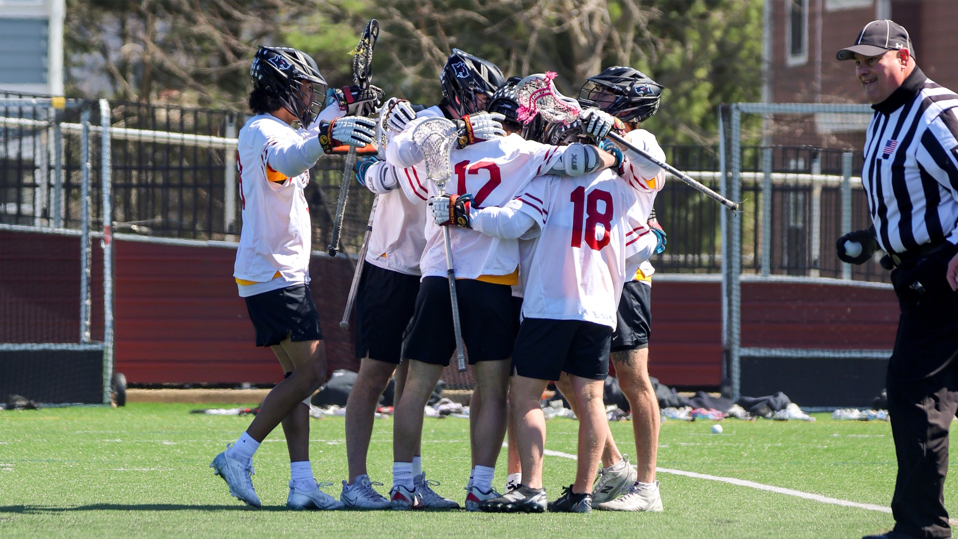 Oberlin College men's lacrosse team celebrating with a hug after a goal