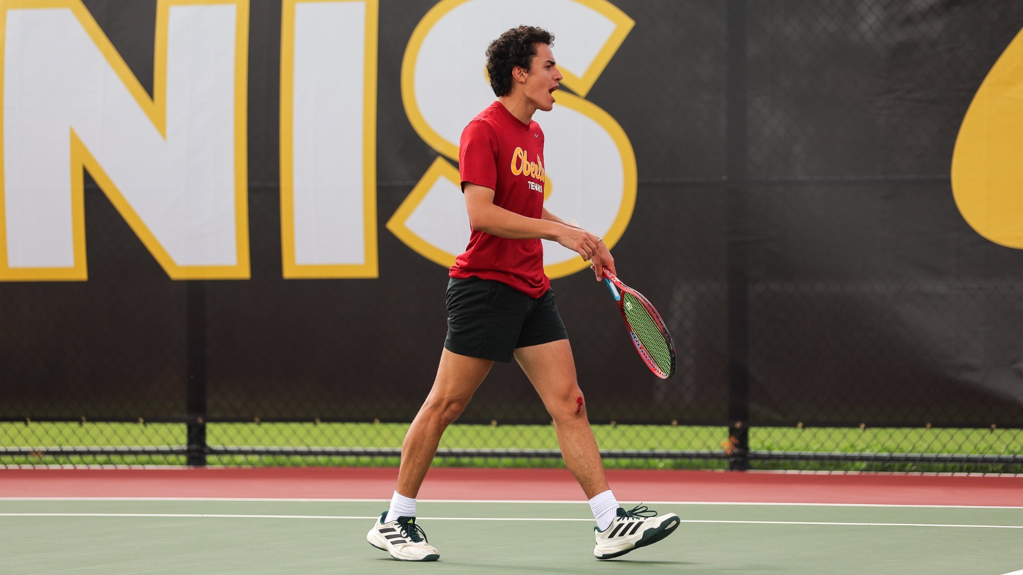 Sebastien Naginski yelling, cheering after winning a point, holding a tennis racket
