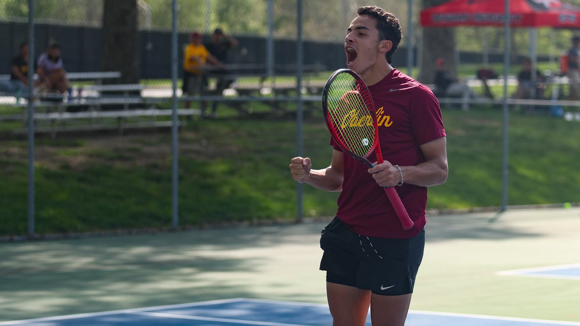 Sebastien Naginski celebrating with his fist in the air while holding his racket