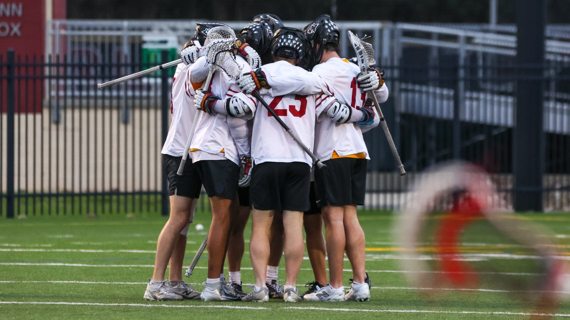 Oberlin men's lacrosse team huddled up together on the field