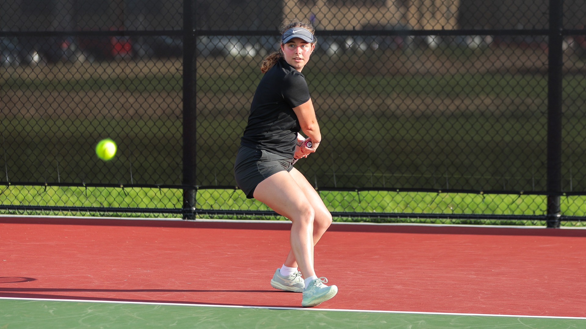 Rachel Allen looks ahead at a tennis ball preparing to hit it