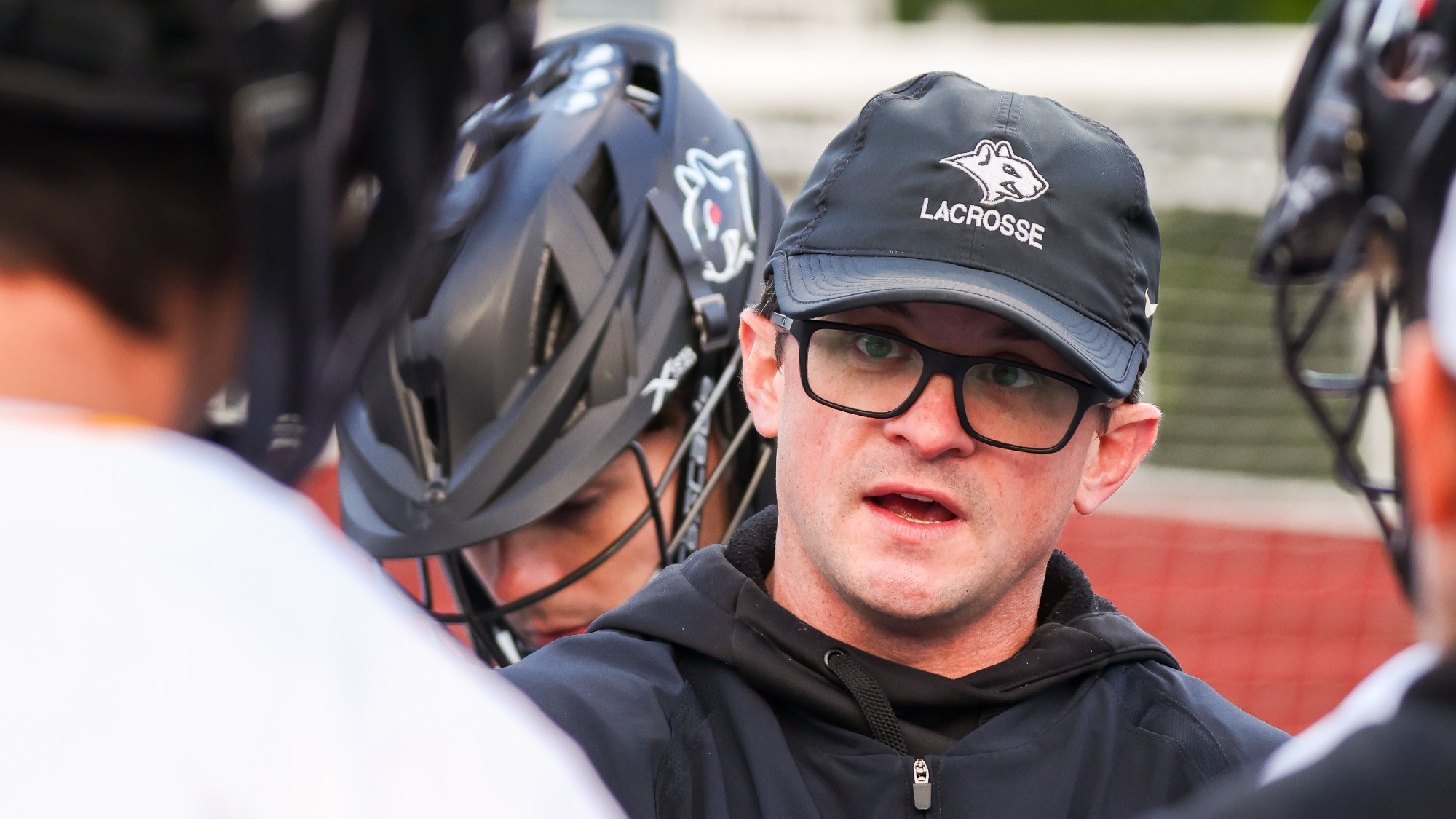 Head Coach Ryan Polak talking to players in a huddle