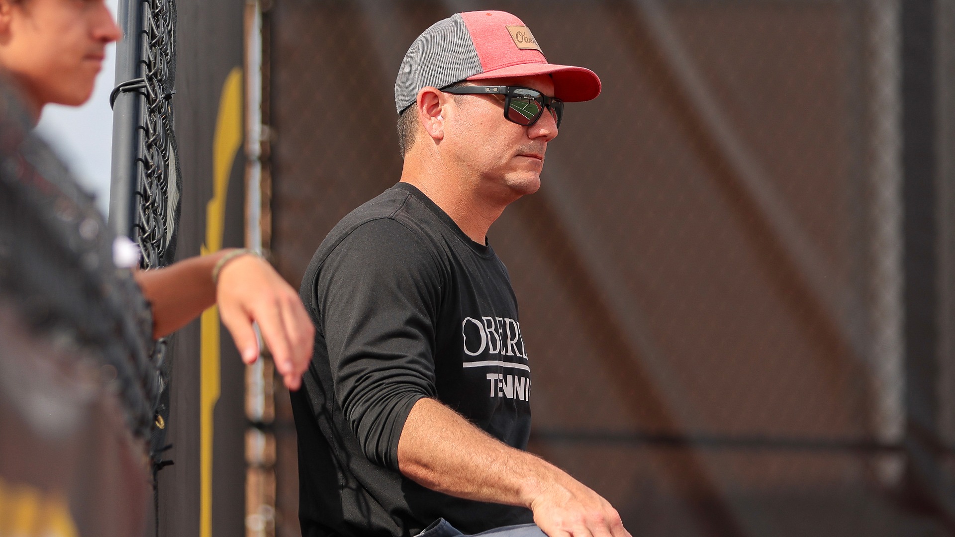 Head Coach Eric Ishida looking off at courts watching tennis