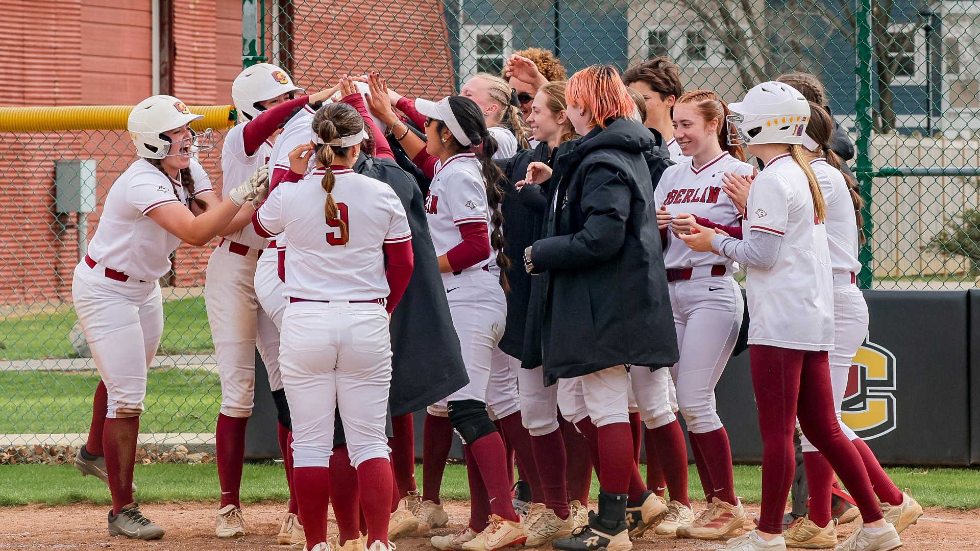 Softball team celebrates at home plate after Maya Means hits a home run
