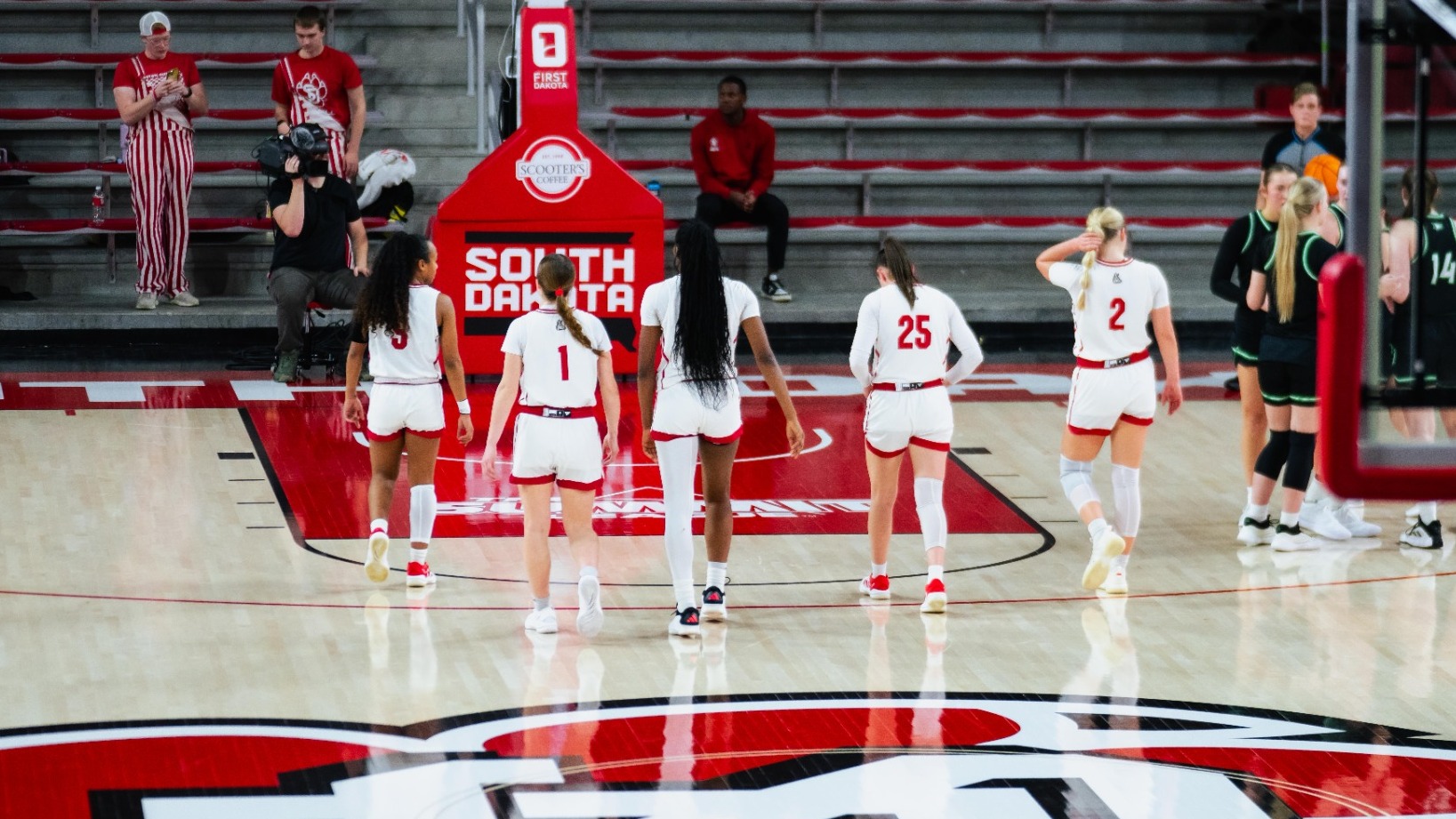 Five Coyote women's basketball players walk on the court together