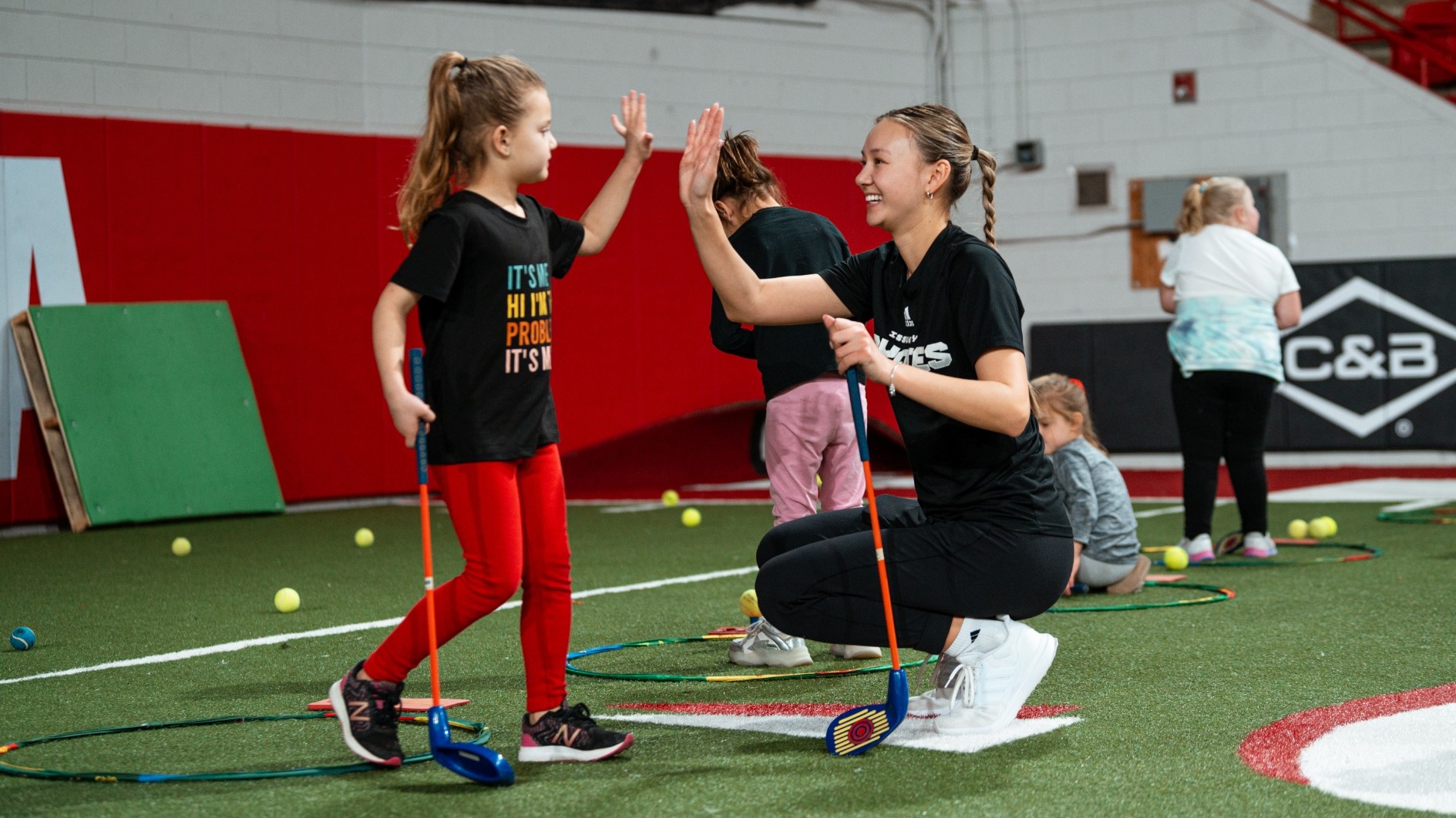 A Coyote women's golfer high-fives a NGWSD Clinic attendee