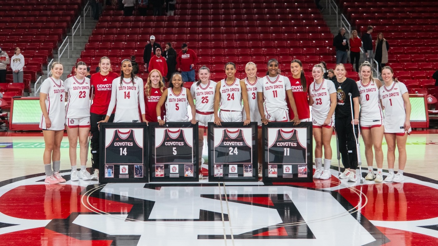The women's basketball team poses with their four seniors for a photo on Senior Day