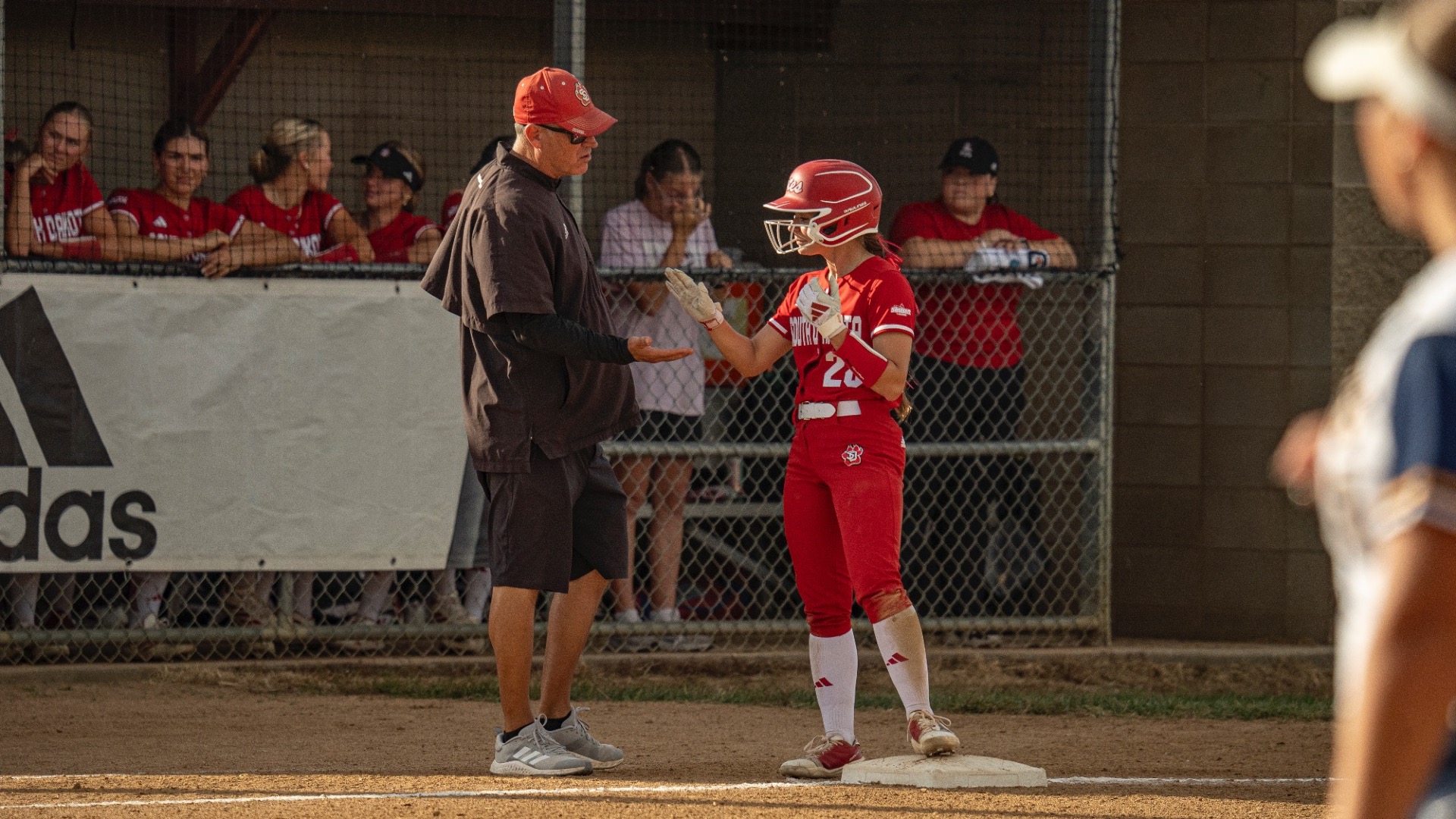 Coach Wags and Brylee Hempey high five on third base