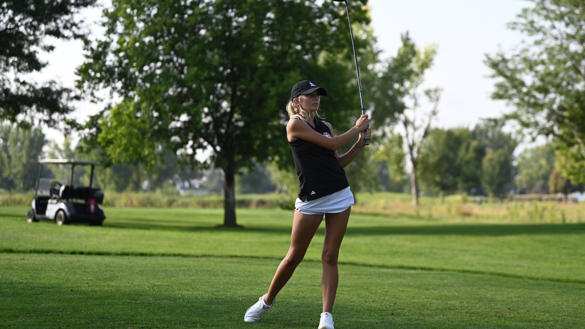 Eva Greenberg hits shot during golf tournament